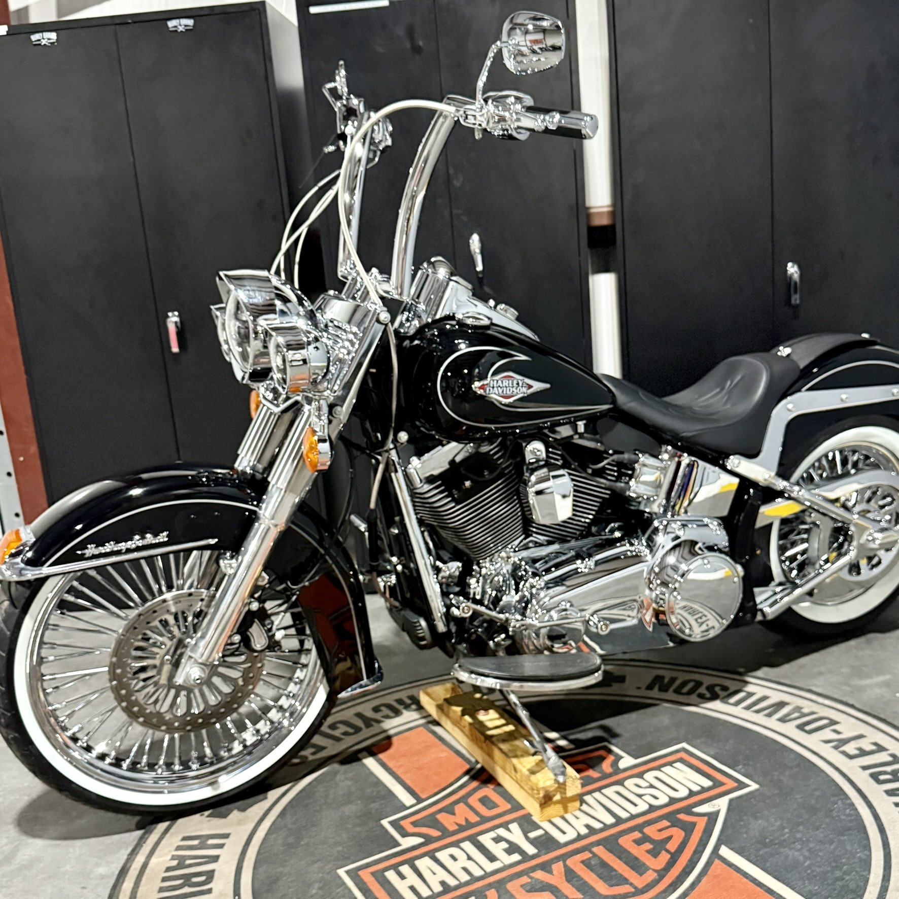 Black Harley-Davidson motorcycle with chrome accents on display on a Harley-Davidson branded mat in a showroom.