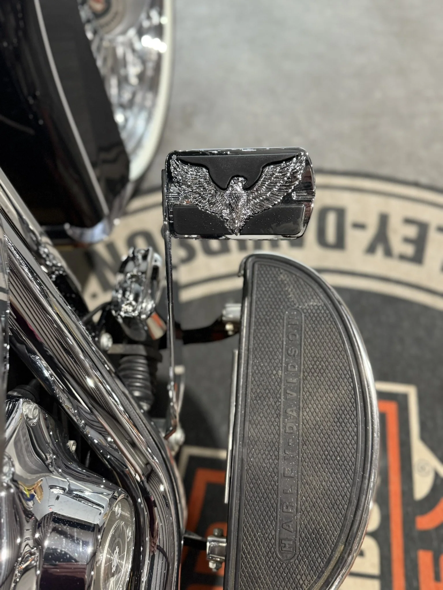Close-up of a Harley-Davidson motorcycle with a chrome eagle emblem on the footboard.