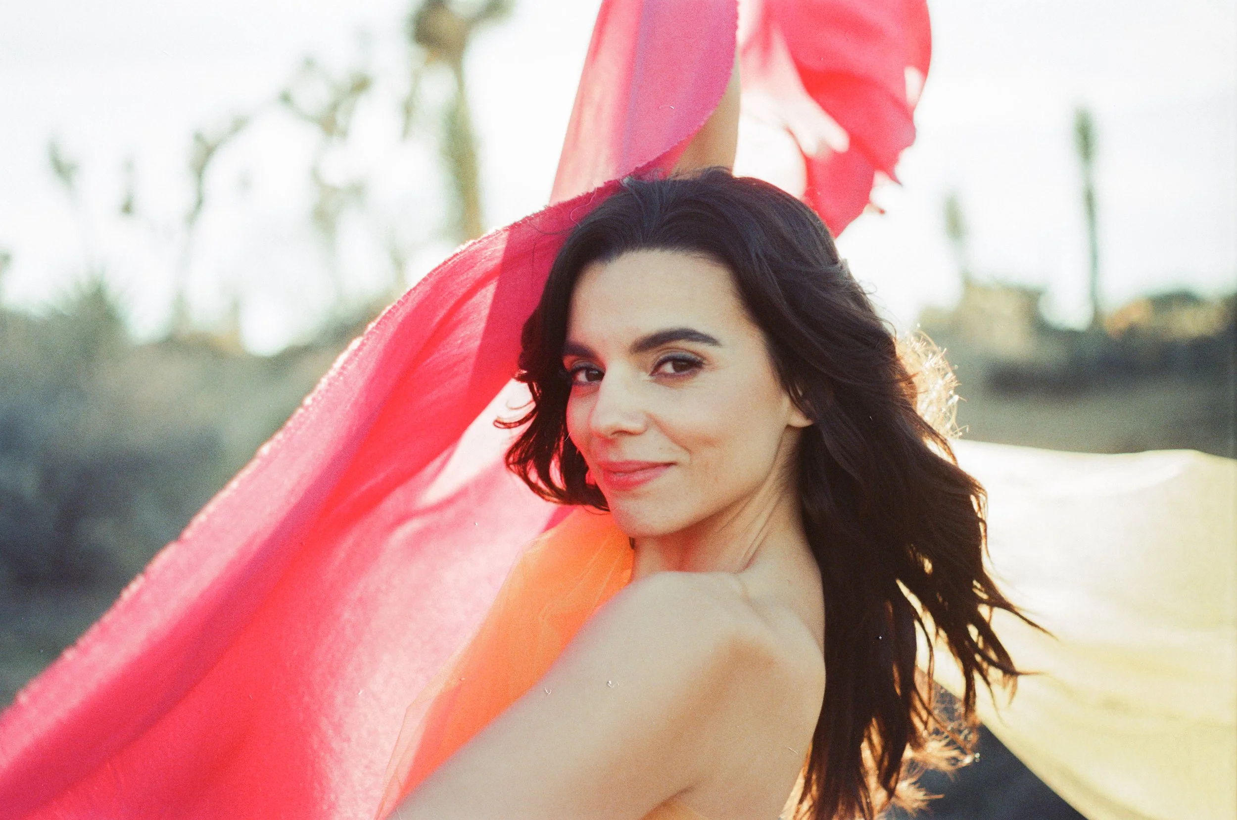 A woman with dark hair holding colorful fabric outdoors