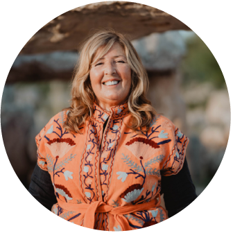 Smiling woman outdoors wearing an orange patterned poncho