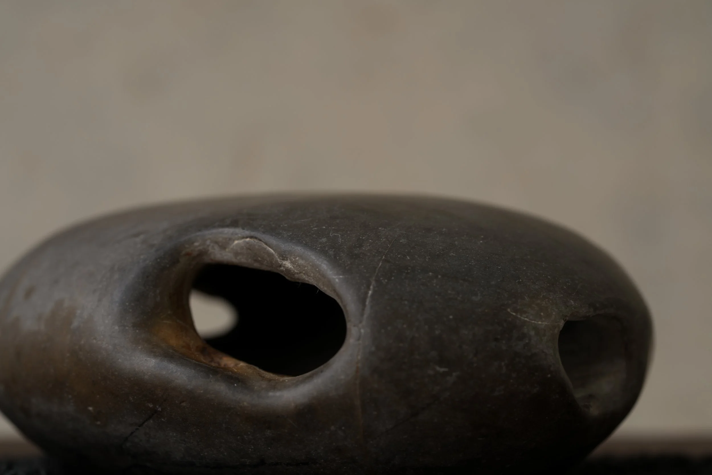 Close-up of a dark, weathered ceramic object with a circular opening, possibly the top of a vessel or a porcelain piece.