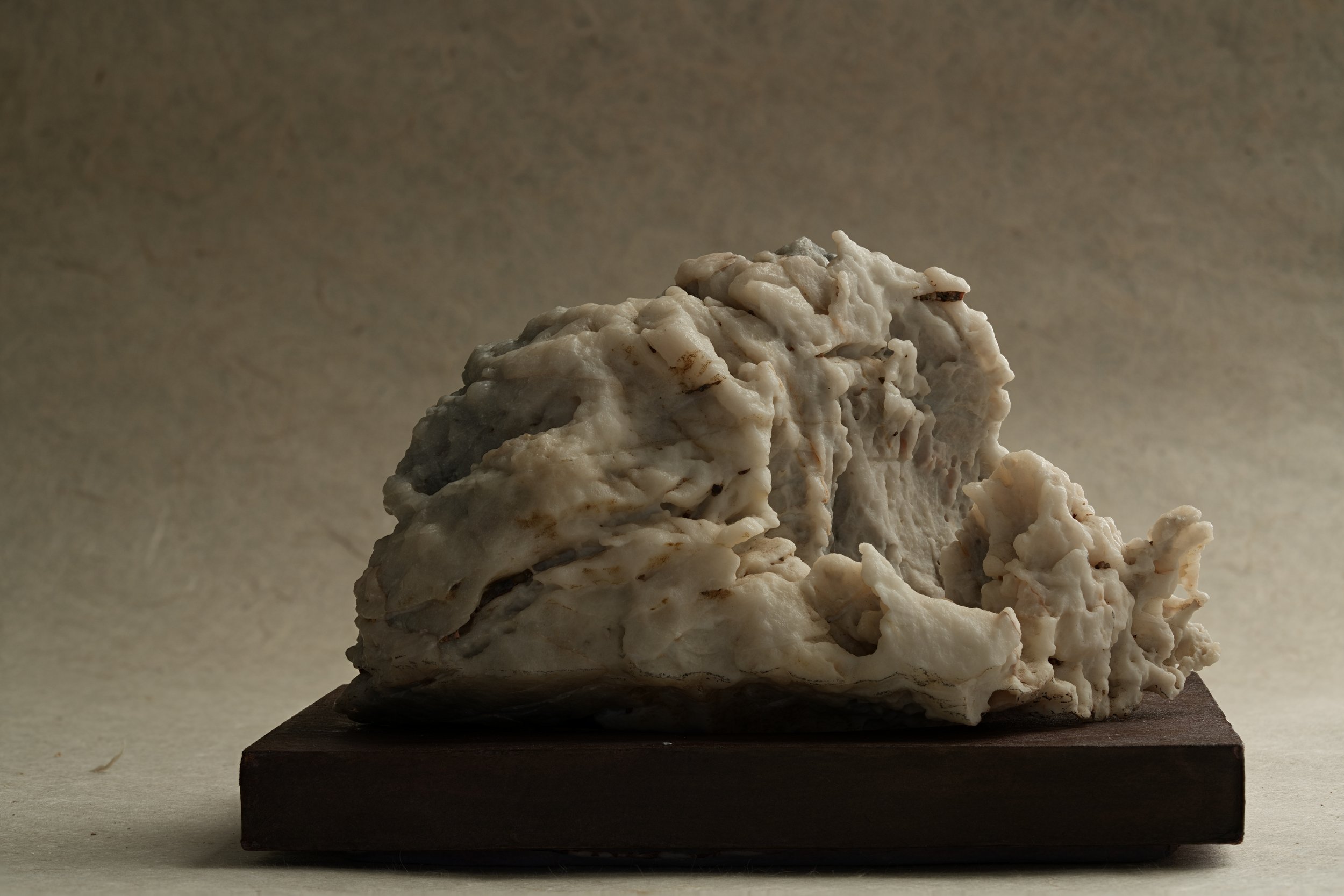 A textured white stone on a wooden base with a soft, neutral background.