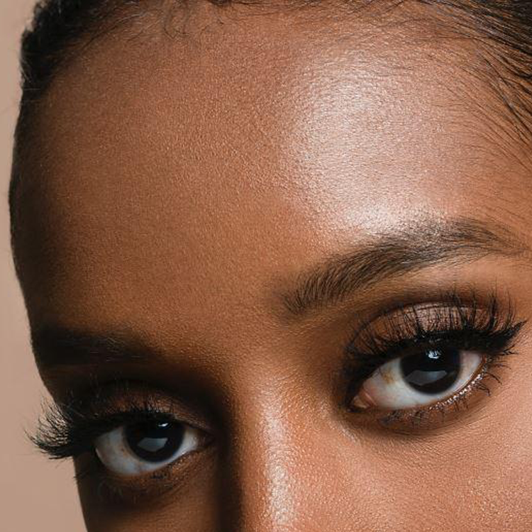 Close-up of a woman's upper face, showing her forehead, eyebrows, and eyes with long eyelashes.
