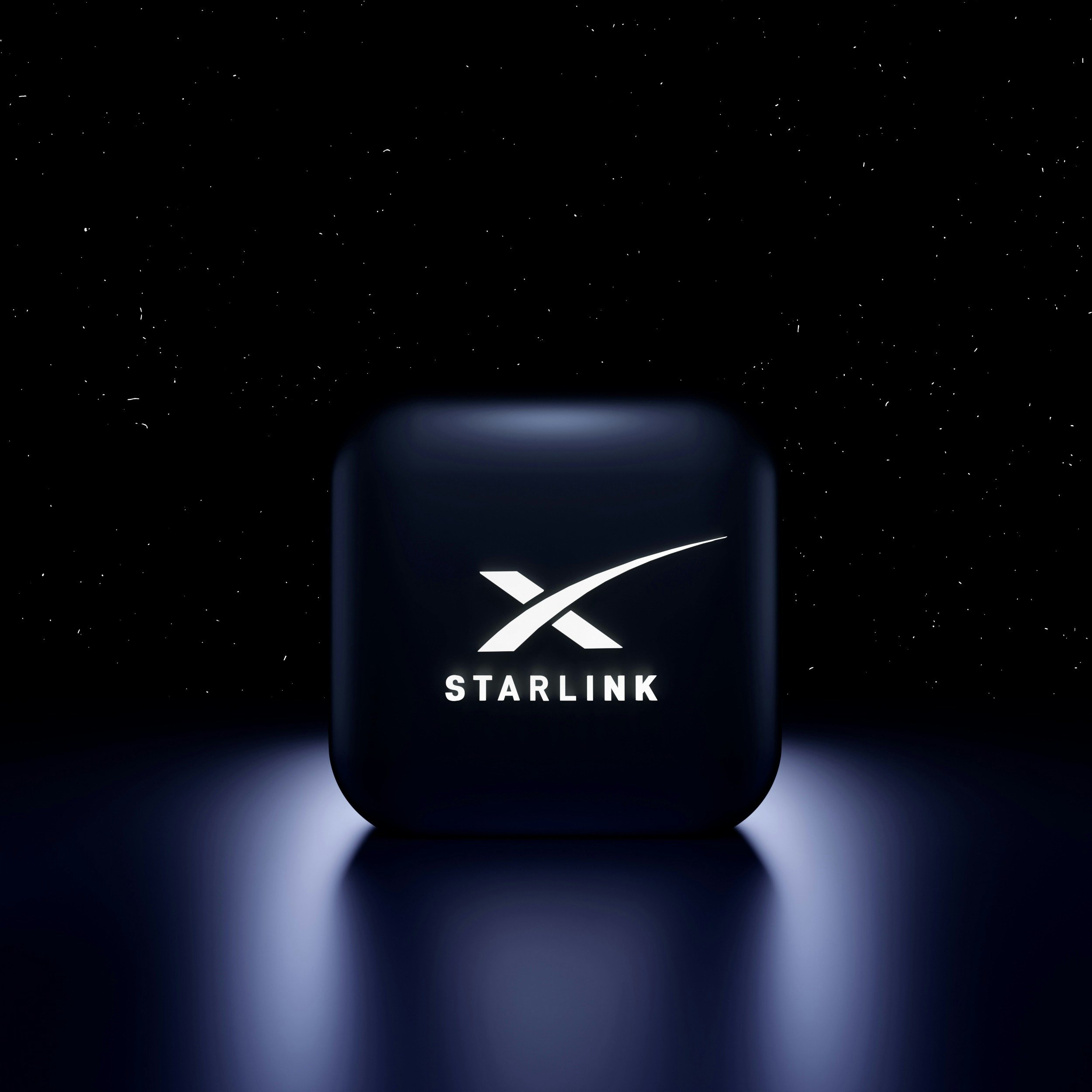 A dark, glossy, square-shaped object with rounded edges displaying the Starlink logo and text, illuminated by a soft glow against a starry background.