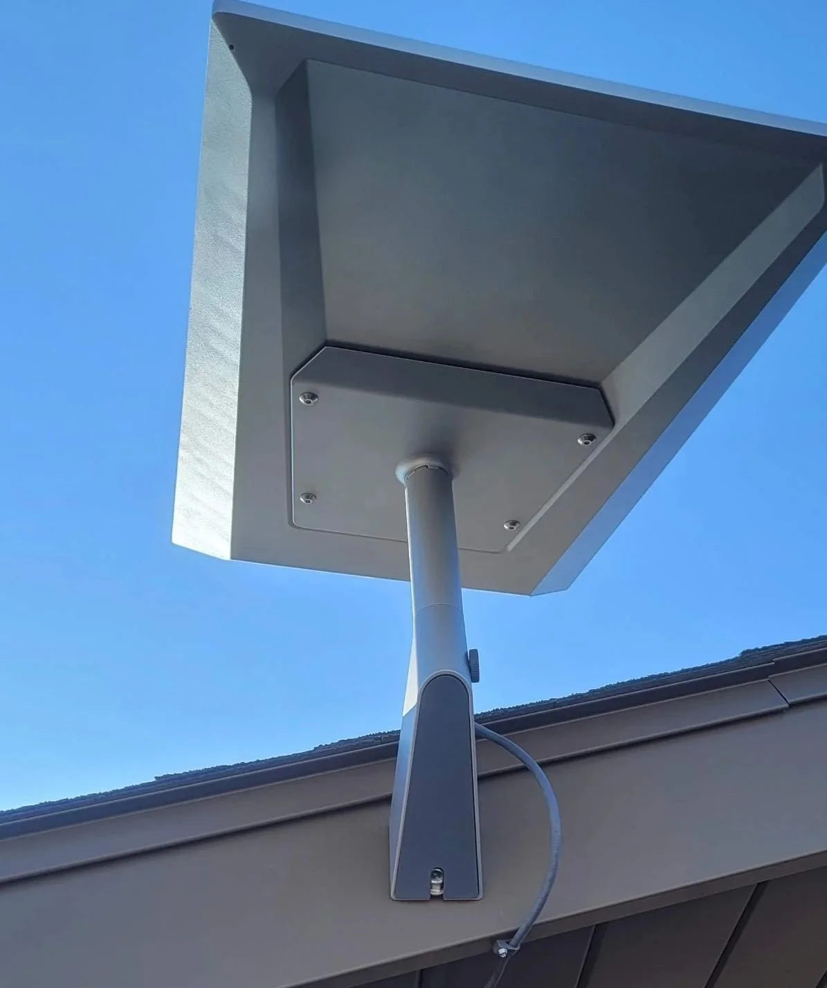 A directional outdoor Wi-Fi antenna mounted on a building against a clear blue sky.