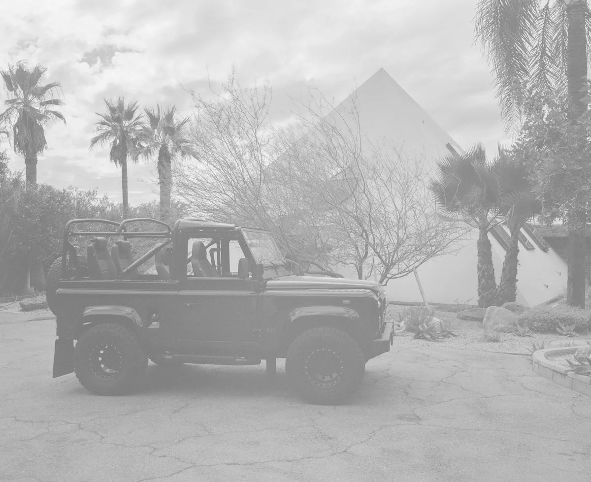 a pyramid with palm trees and landrover in the foreground