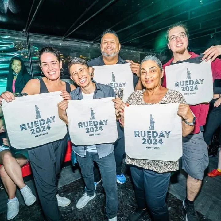 Group of five people holding signs that read 'Rueday 2024, New York' at an indoor event.