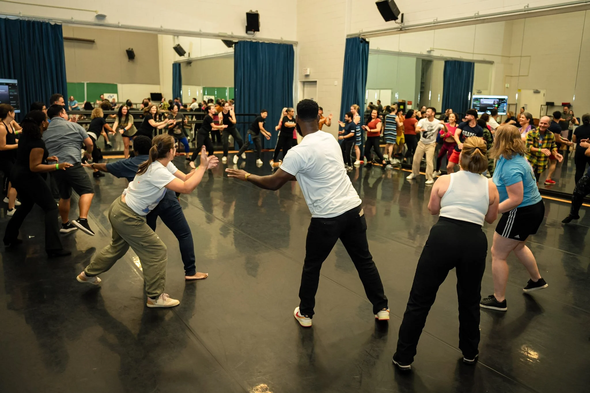 People dancing in a studio, with a large group practicing or enjoying a dance activity.