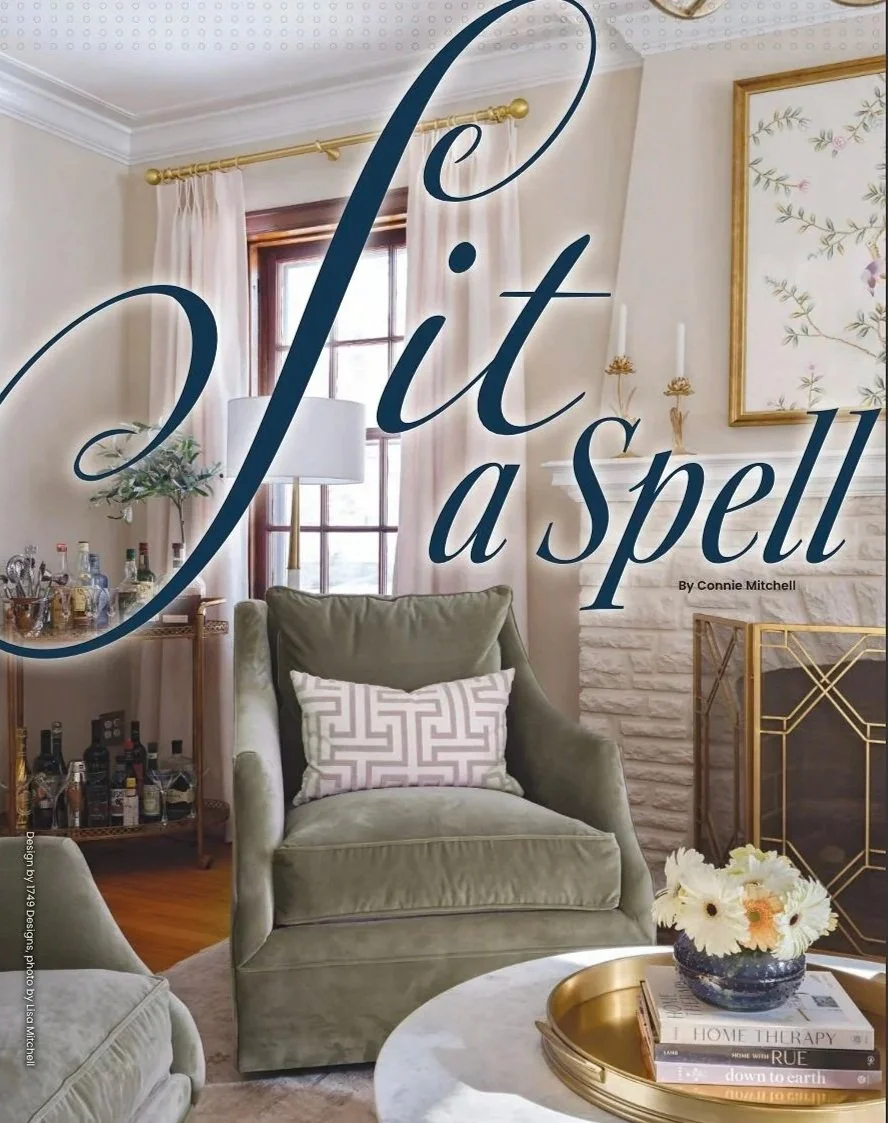 A cozy living room with natural light from a window, featuring green armchairs, a coffee table with a flower vase and books, a bar cart with bottles, and art on the walls. Overlaid text reads 'Slit a spell'.