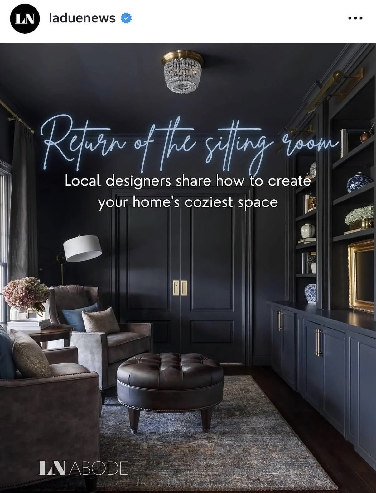 A luxurious sitting room with dark walls, a chandelier, built-in dark shelving with decorative items, a leather ottoman, armchair, sofa, and a window with curtains. Overlaid text promotes a home decor article.