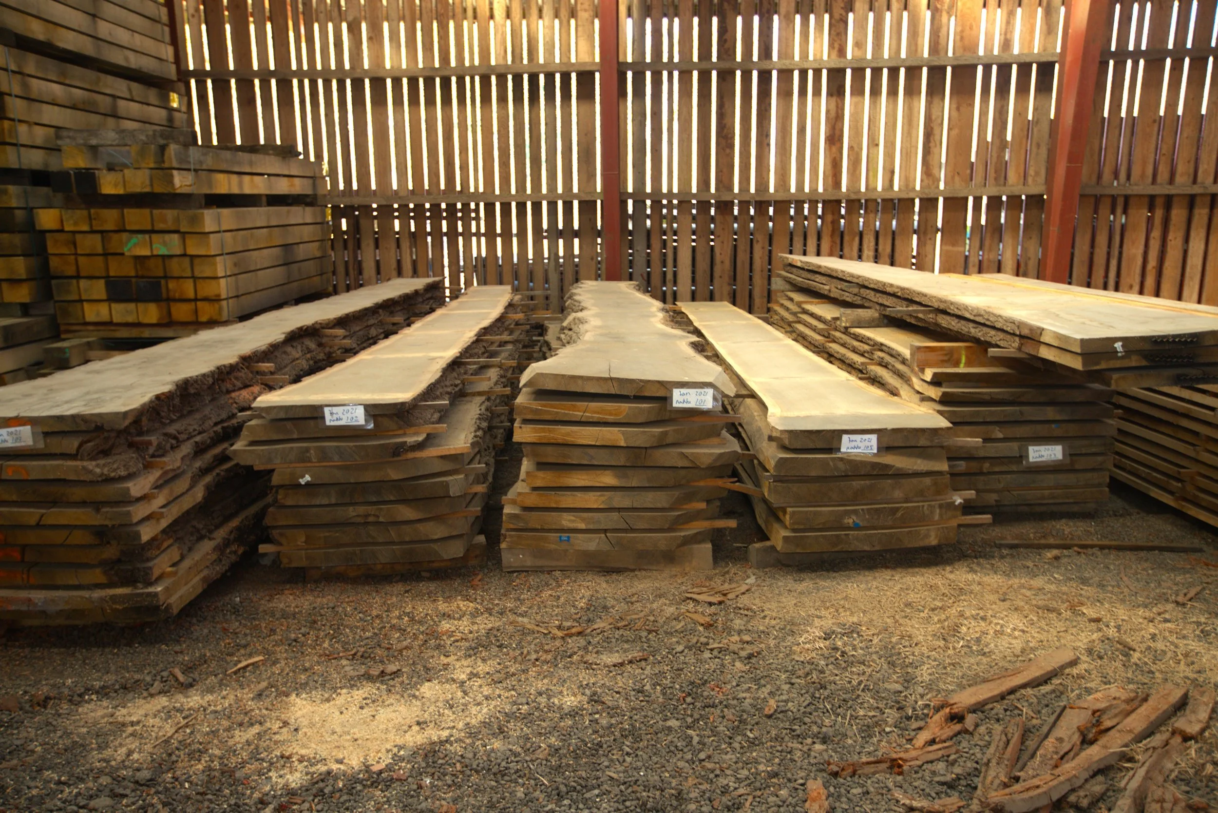 Several large raw wood slabs with visible grain and natural edges leaning against a workshop wall.