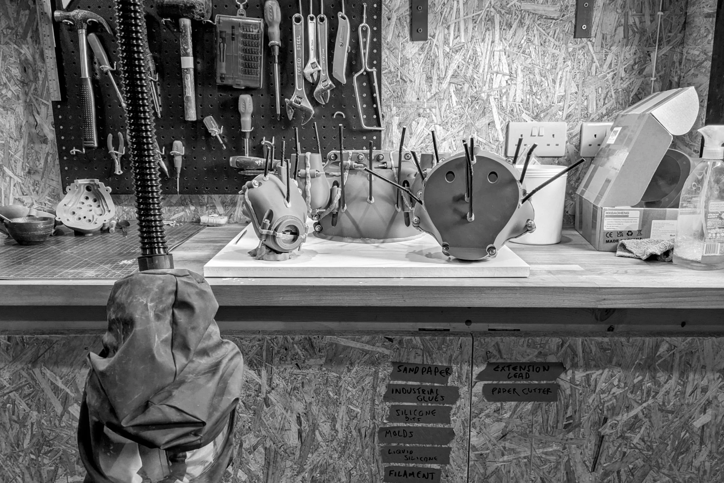 Jamie Howlett studio workspace; interior view featuring industrial tools, sculptural molds, and casting apparatus. Behind-the-scenes glimpse into technical production of cement and flint works.