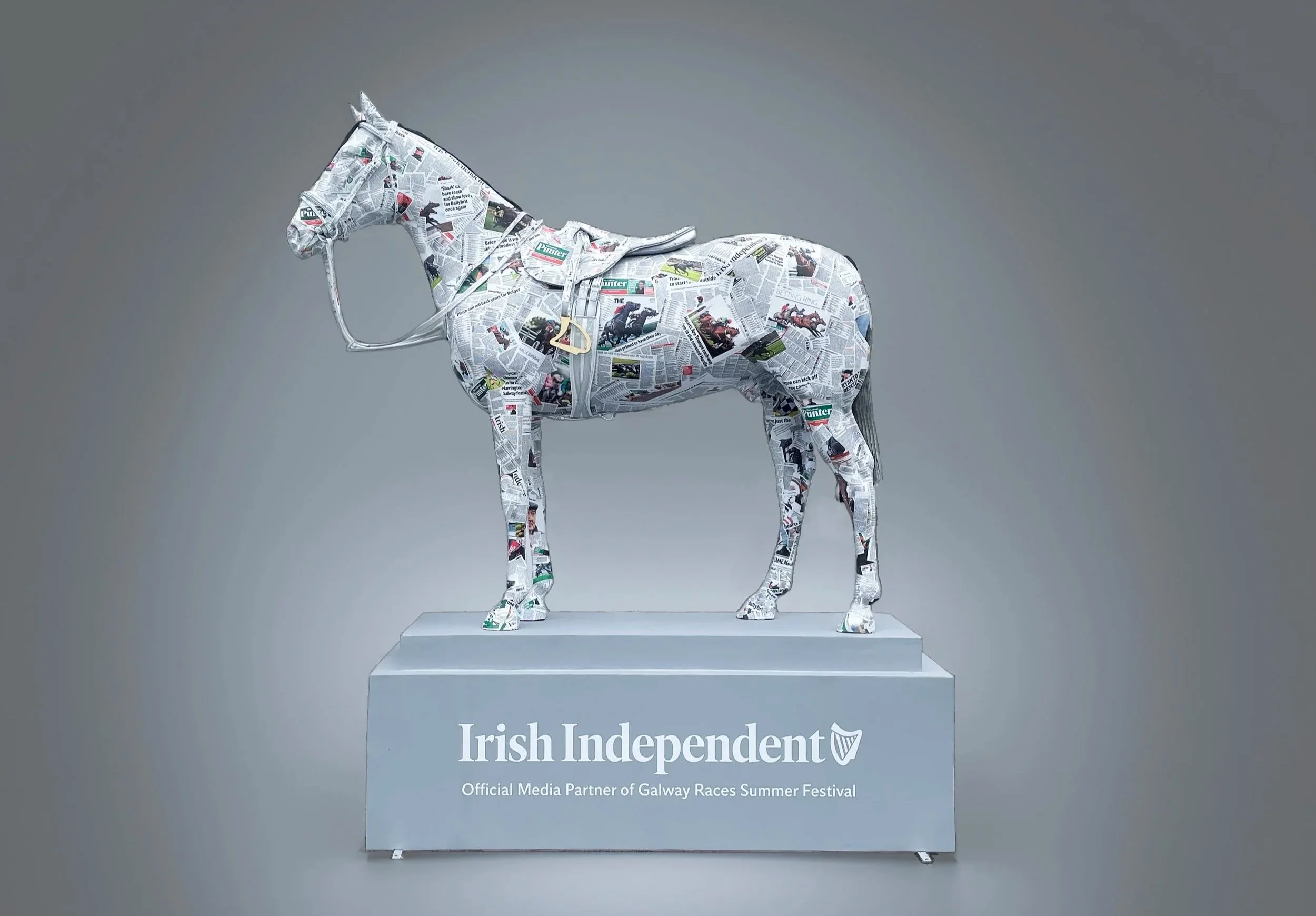 A promotional sculpture of a horse wrapped in newspaper clippings from Mediahaus, mounted on a platform with the Irish Independent logo and the text 'Official Media Partner of Galway Races Summer Festival.'