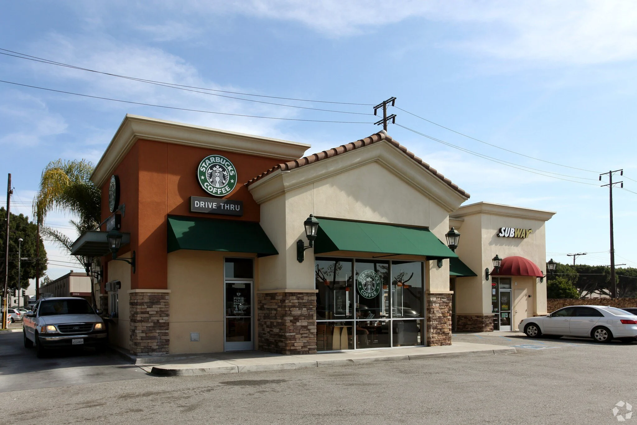 Starbucks coffee shop with drive-thru, green awnings, and a Subway restaurant on one of the busiest intersections in Santa Fe Springs in Southern California. 