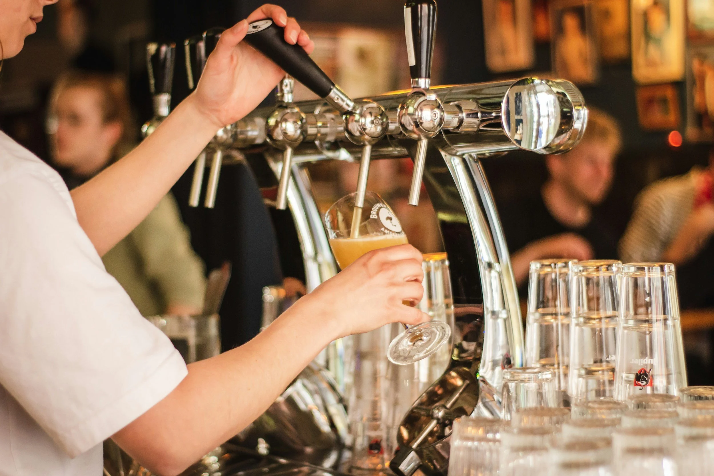 A bartender pouring beer from a tap into a glass at a bar.