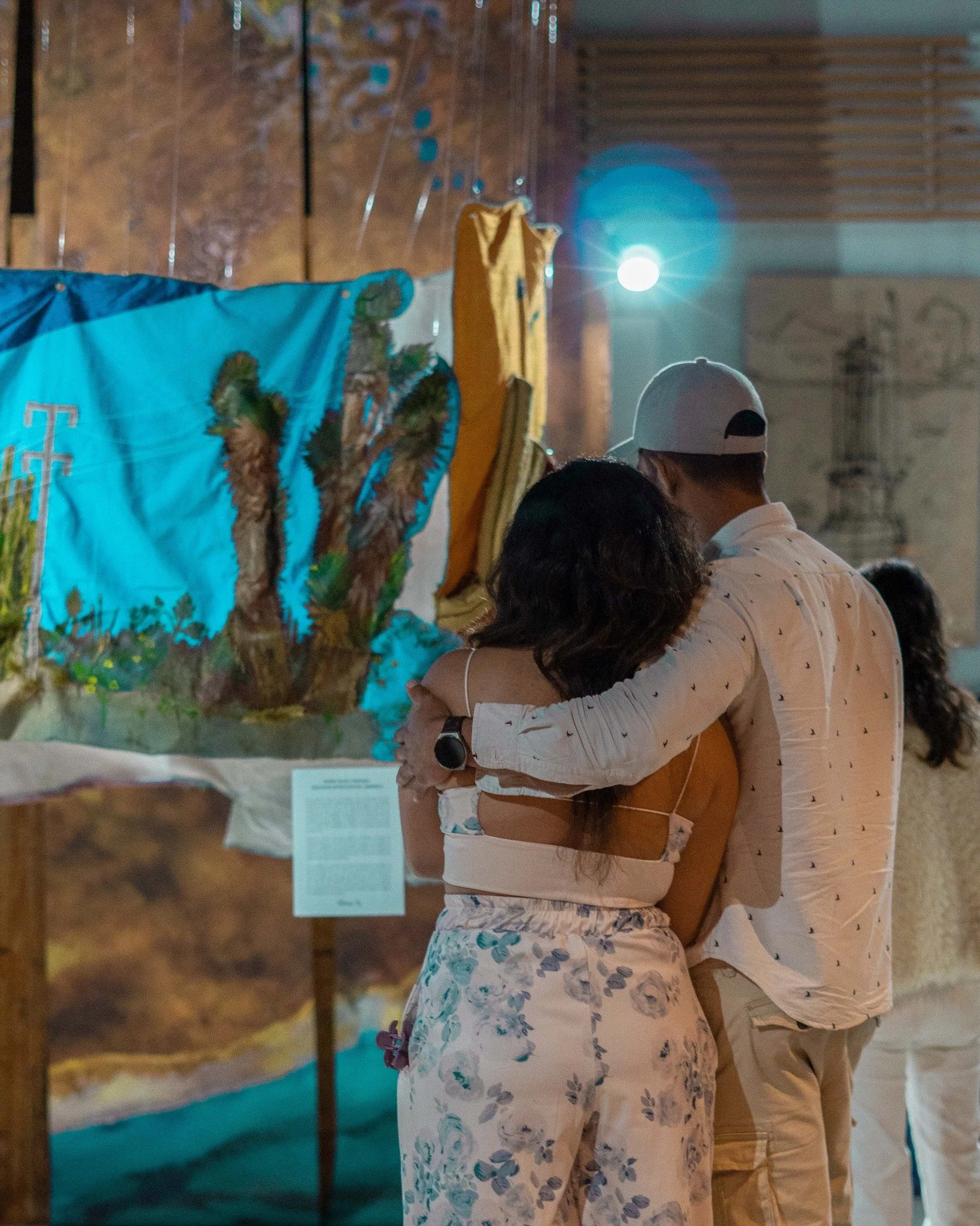 Visitantes observando obra textil y artística dentro de exposición comunitaria.