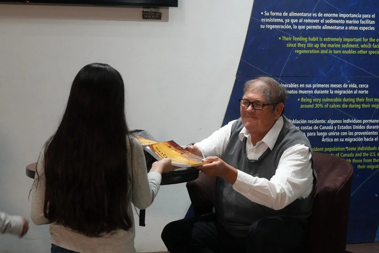 Autor entregando libro durante charla cultural realizada en MUSAM.