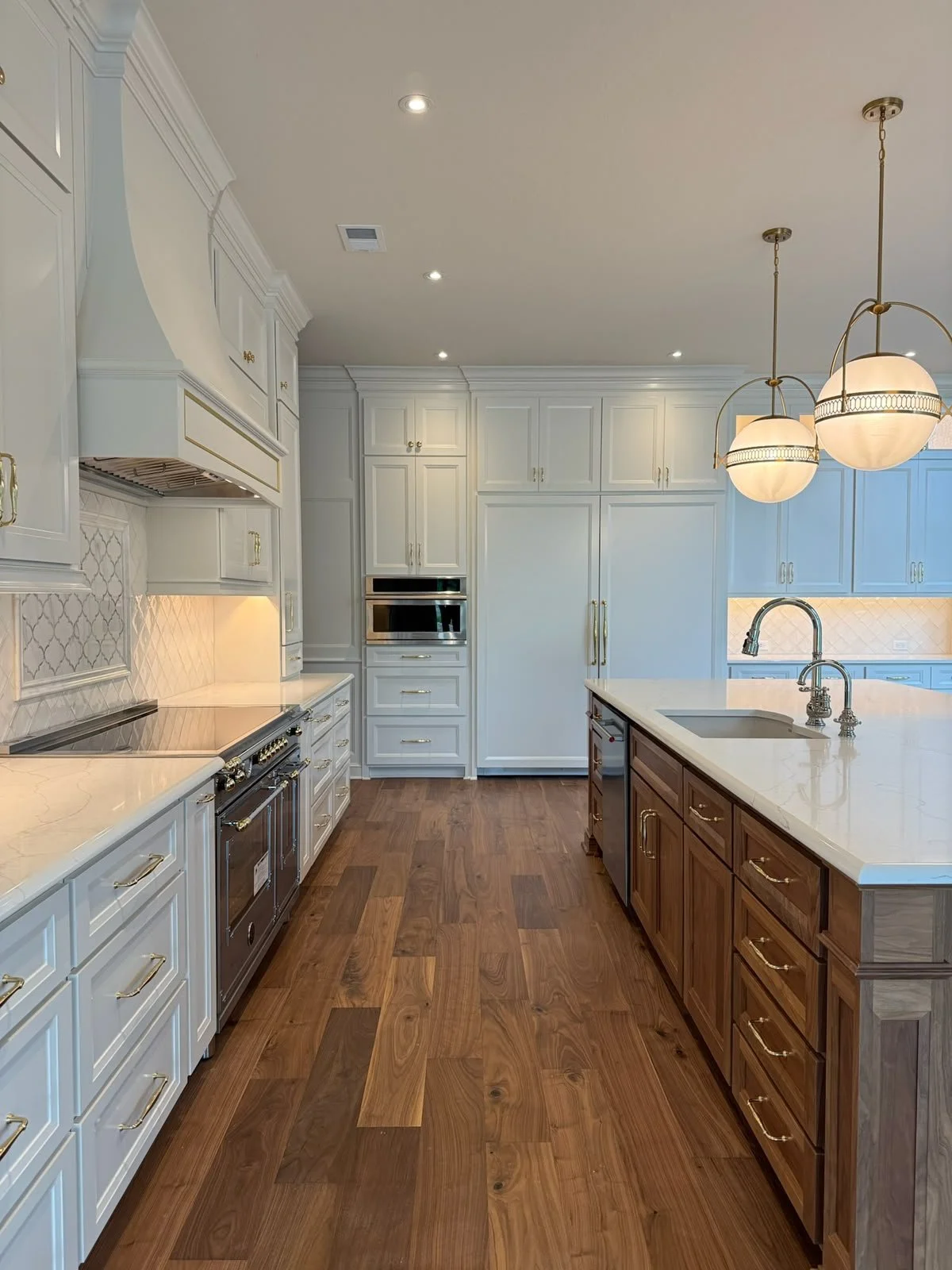Modern kitchen with white cabinets, wooden island, marble countertops, and pendant lighting.
