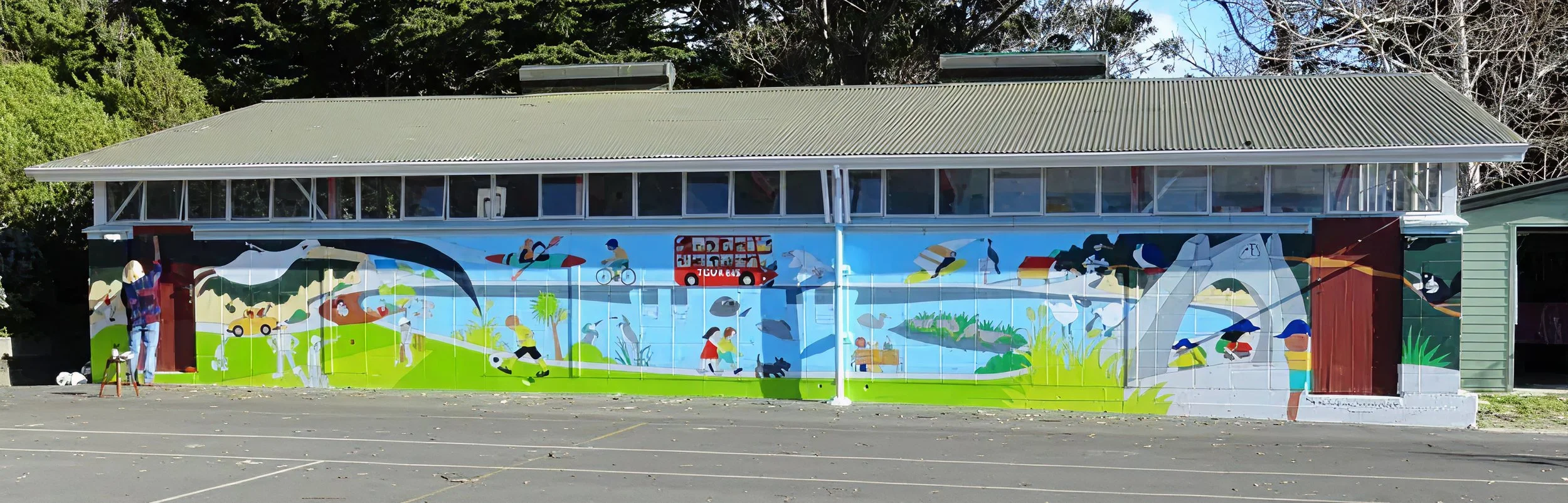 Colorful mural painted on a building with people, animals, and a fire truck, depicting a lively outdoor scene.