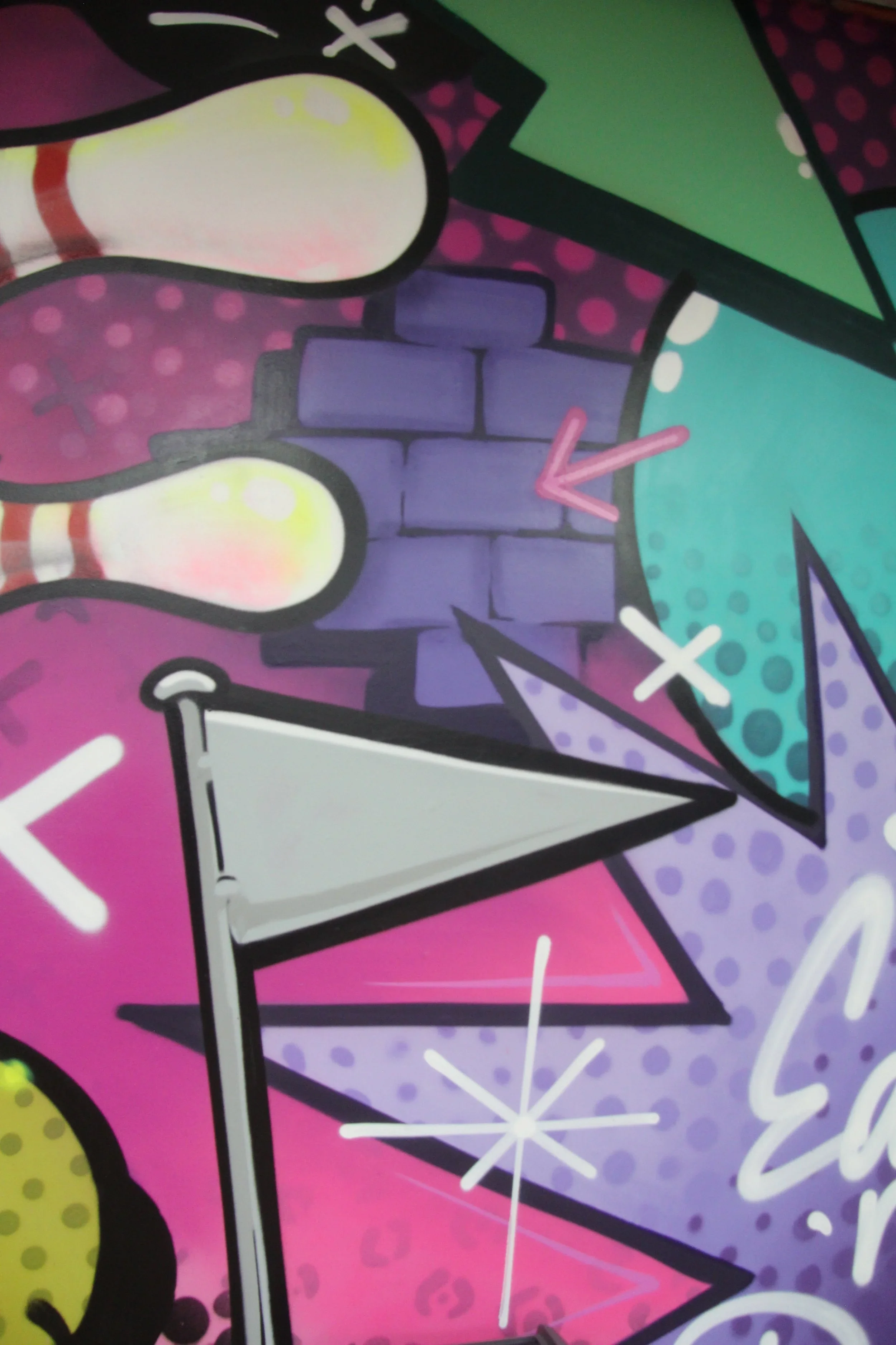 Close-up of colorful graffiti art on a wall, featuring abstract shapes, a brick wall pattern, and various pastel and neon colors.