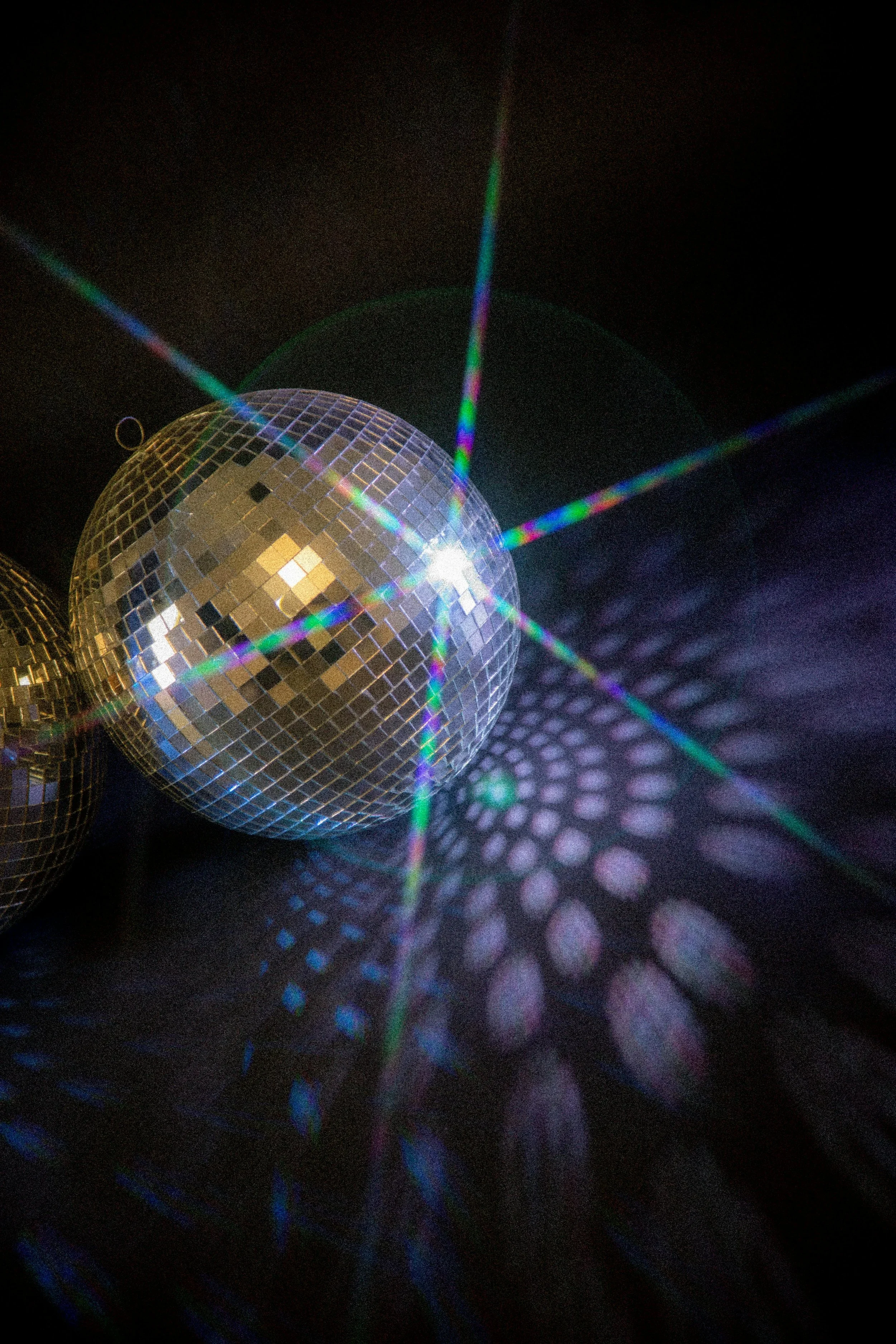 Disco ball reflecting colorful light patterns on a dark background.