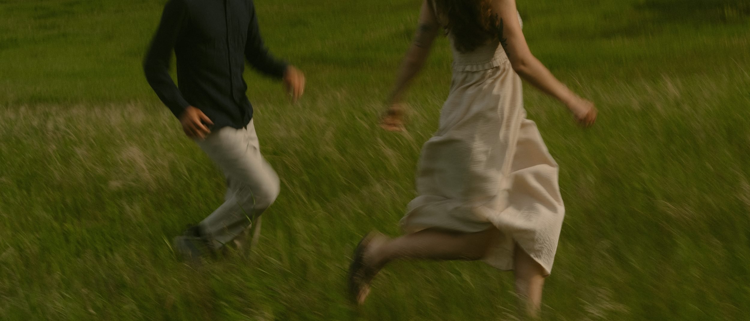 Couples running through canmore field at golden hour