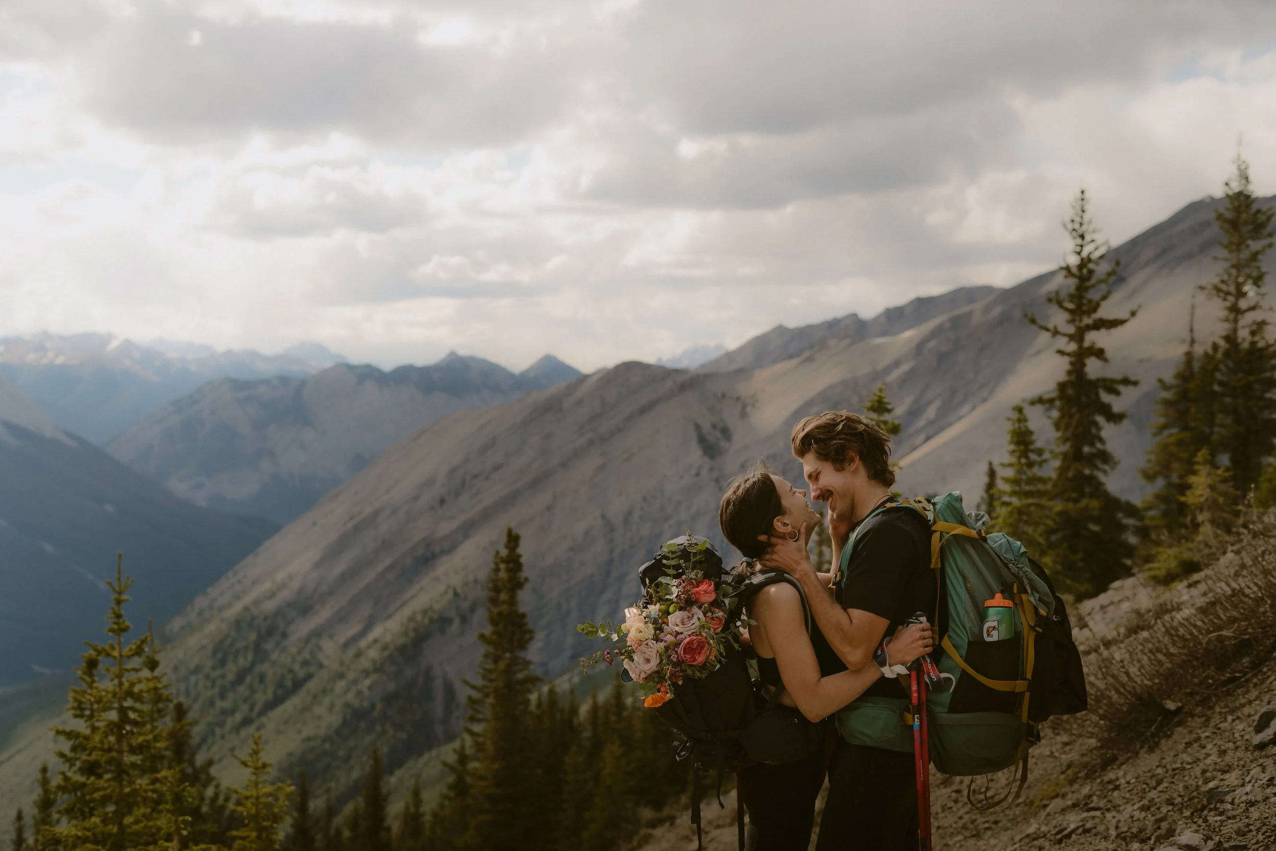 Couple hiking Ha Ling Peak trail in wedding attire for their adventure elopement in Canmore