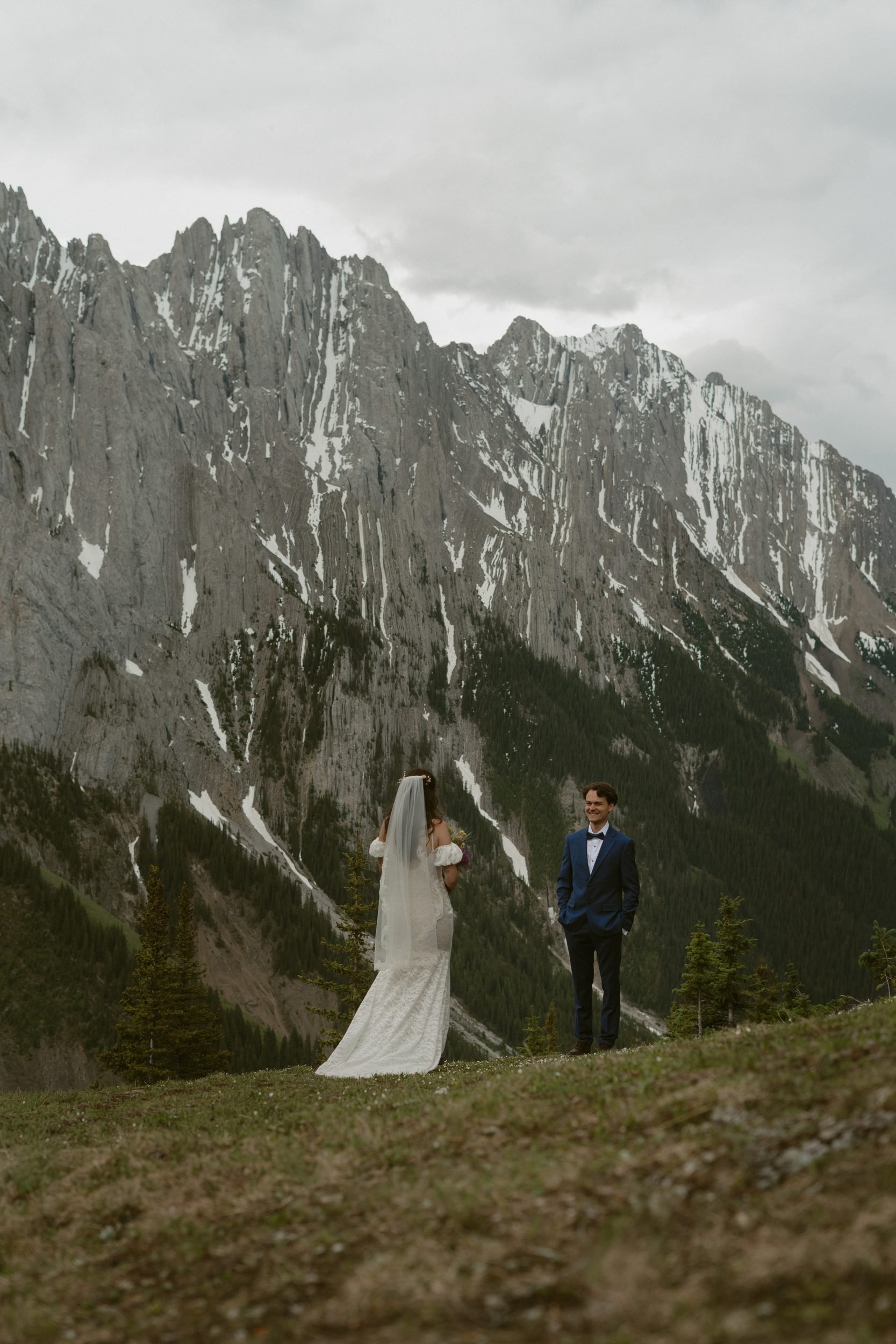 Couple standing together beneath mountain peaks during their Kananaskis elopement