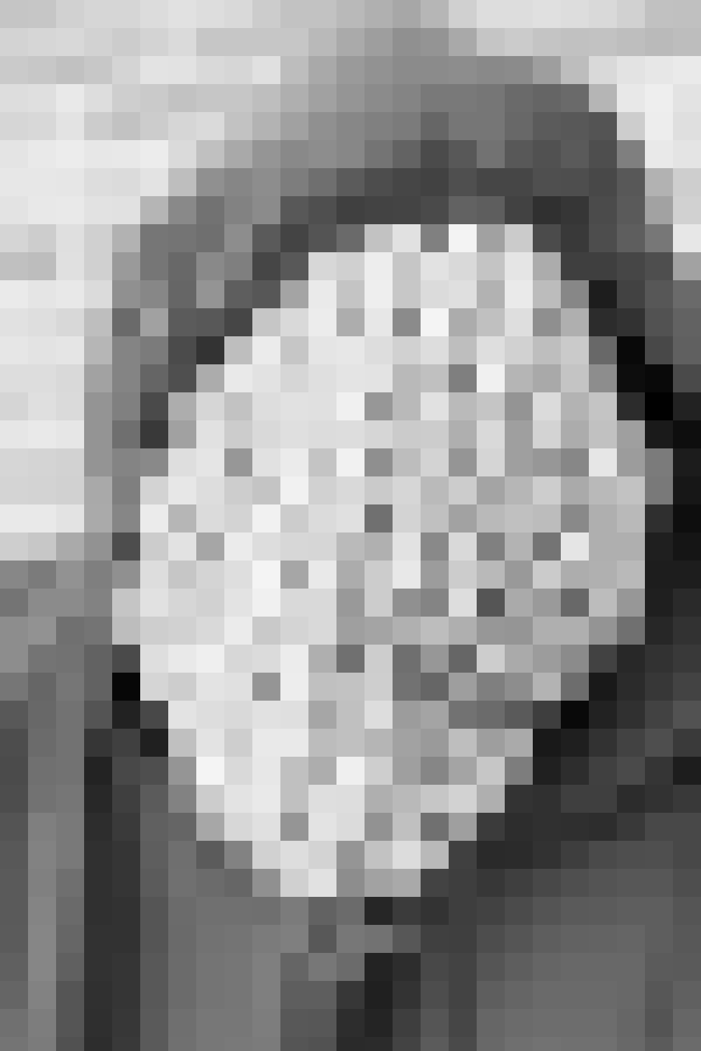 A woman inside a retail store holding a paper shopping bag.