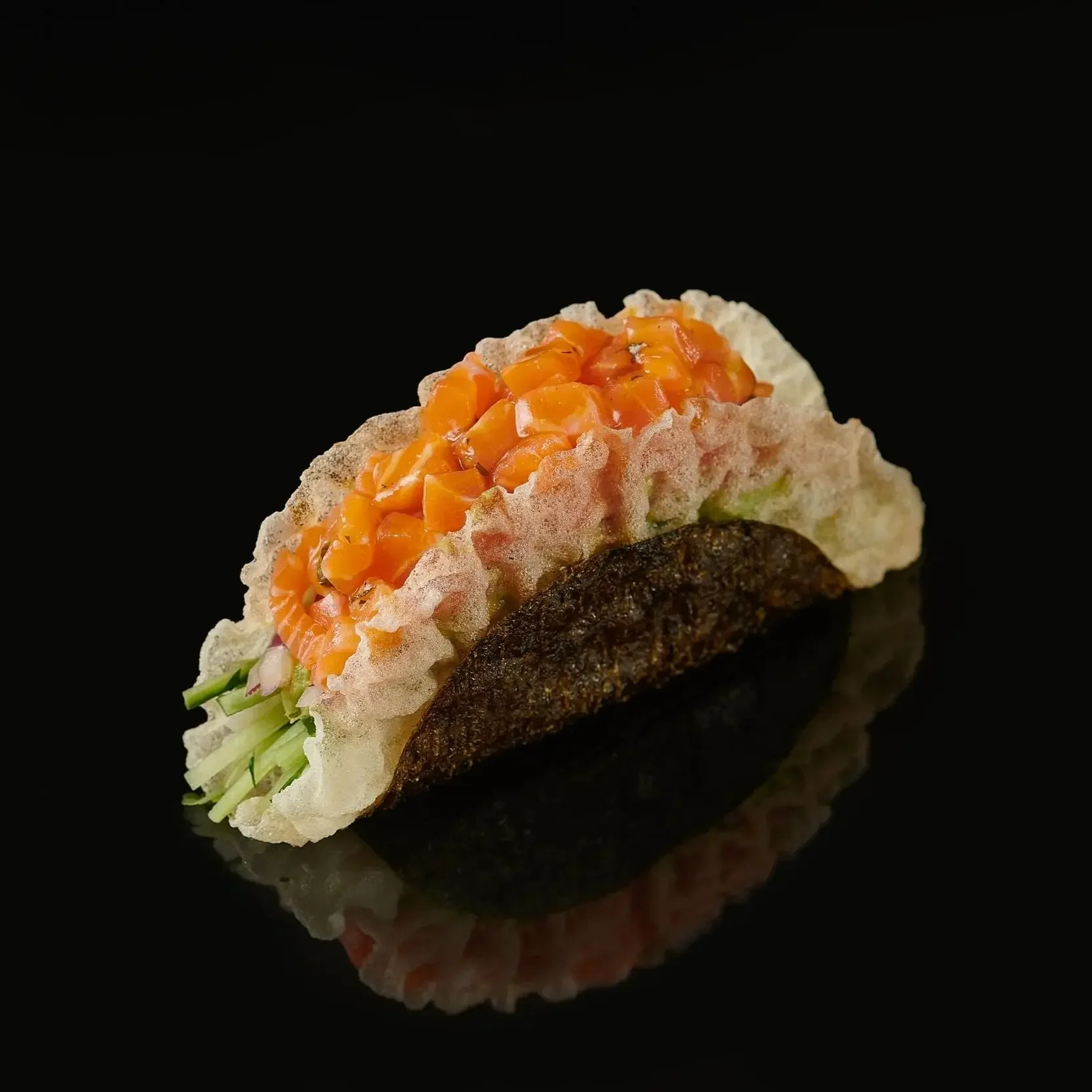 Salmon Carpaccio Taco Delicate diced salmon wrapped in crisp nori , layered with seasoned sushi rice, creamy avocado, cucumber, and red onion. Finished with tobiko, dill, and a bright yuzu ponzu carpaccio sauce
