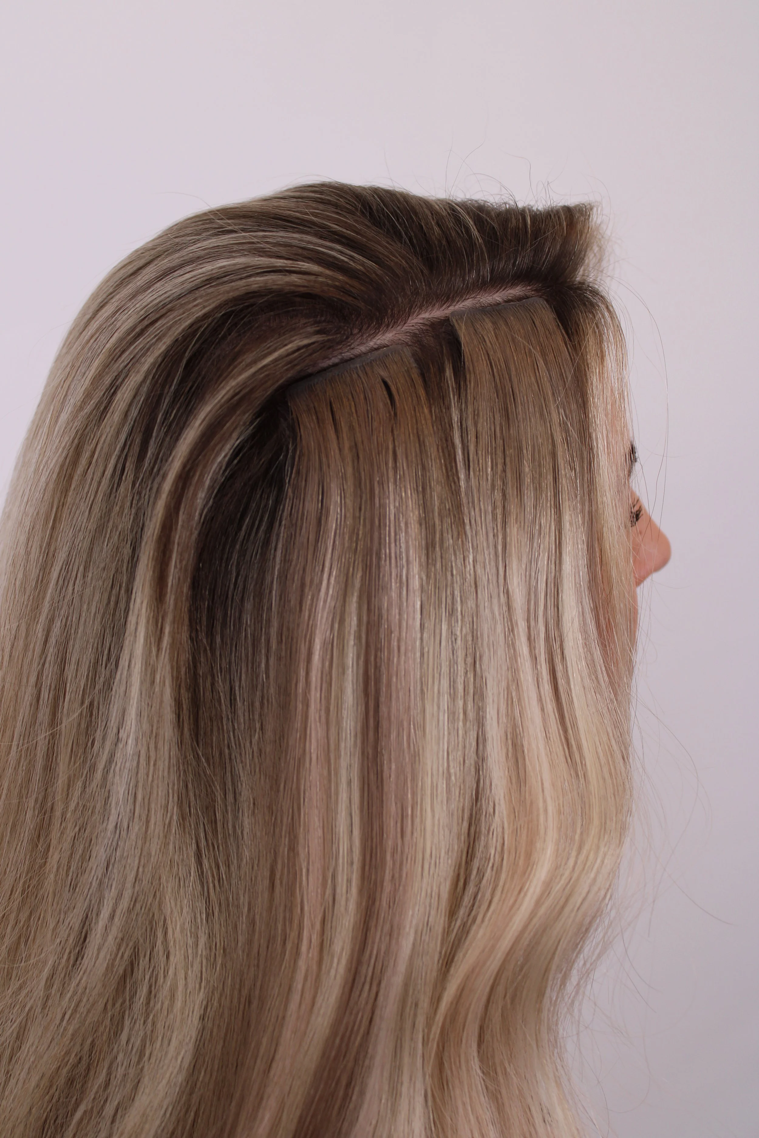 Close-up of a person with long, straight, blonde hair being styled with hair clips.