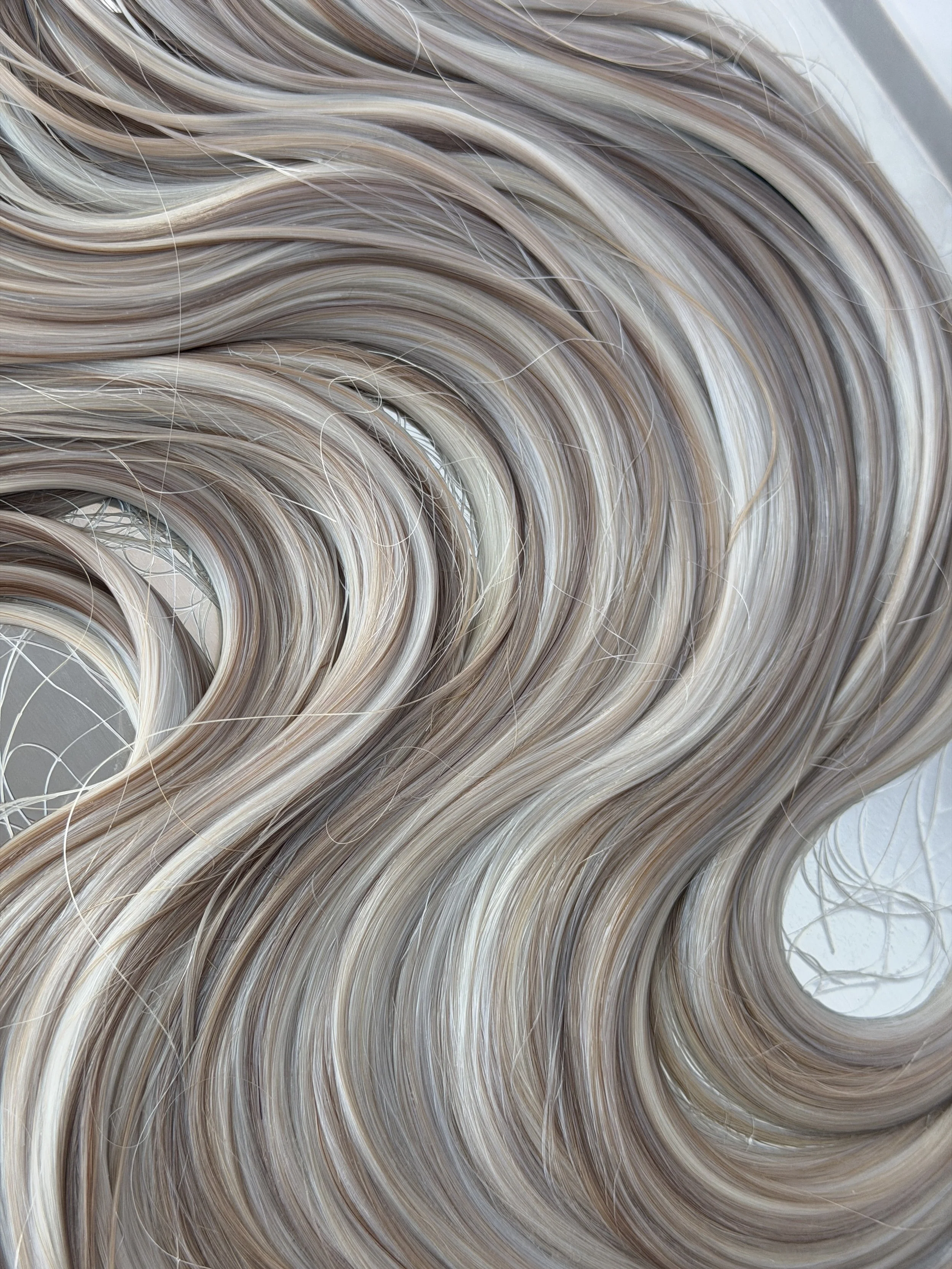 Close-up of blonde hair with light and dark shades, styled in soft waves.