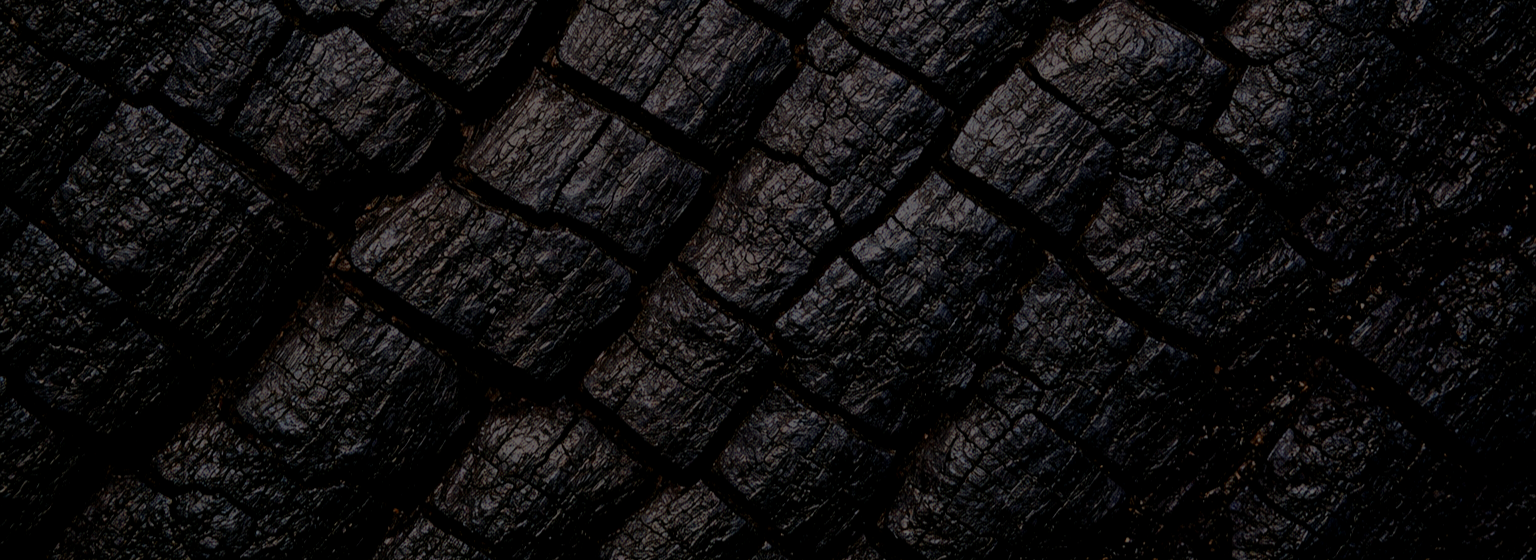 Close-up image of stacked charcoal briquettes with a dark surface and rough texture.
