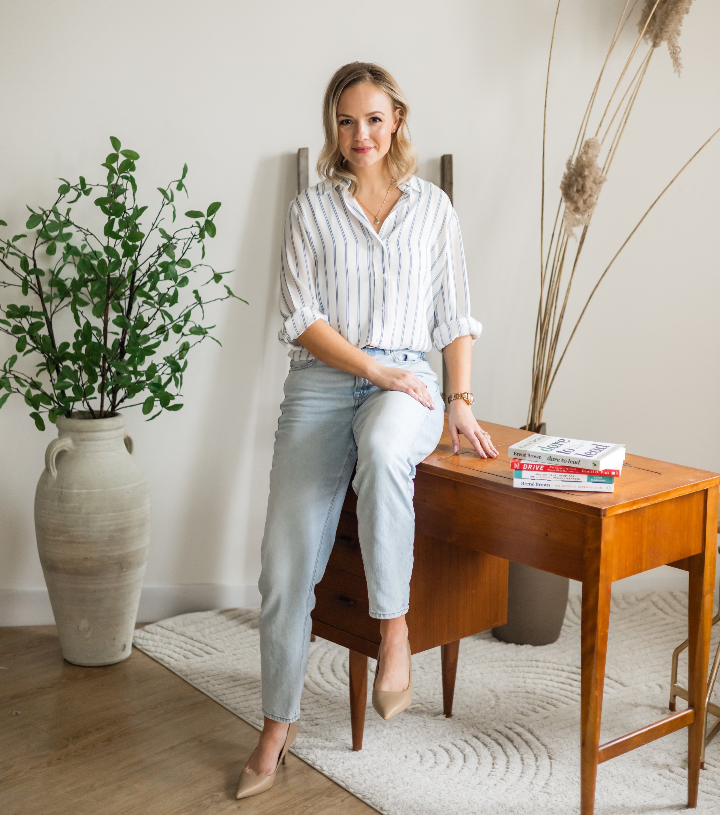 Marla Lorraine, Founder of EleventhRoot Consulting, seated and smiling in a bright, plant-filled space.