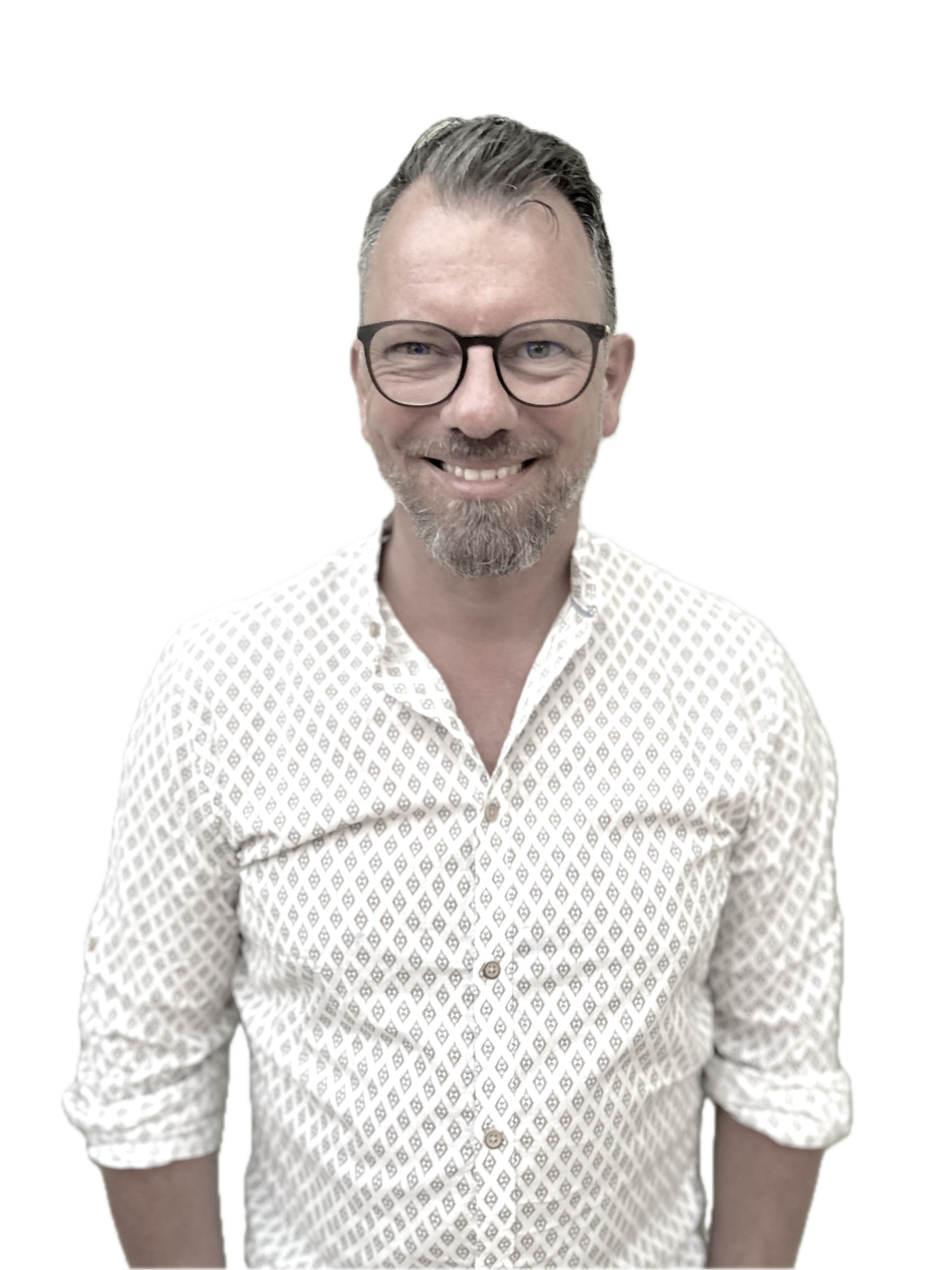 Ein Mann mit Brille, kurzen braunen Haaren und Bart, trägt ein weißes Hemd mit kleinen Mustern und lächelt.