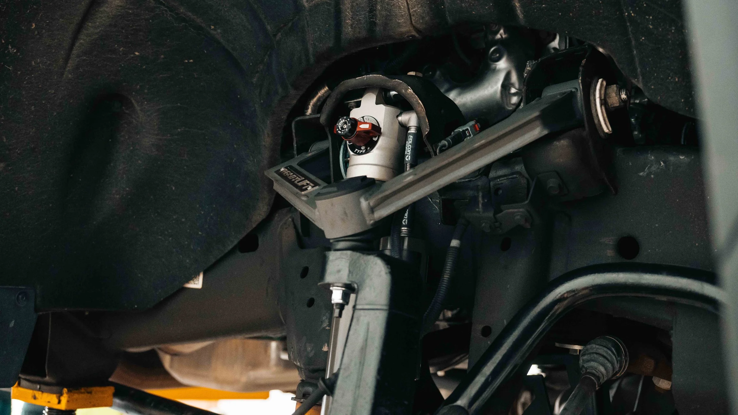 ReadyLIFT upper control arm and Falcon shock assembly inside a GMC Sierra wheel well after lift kit installation.
