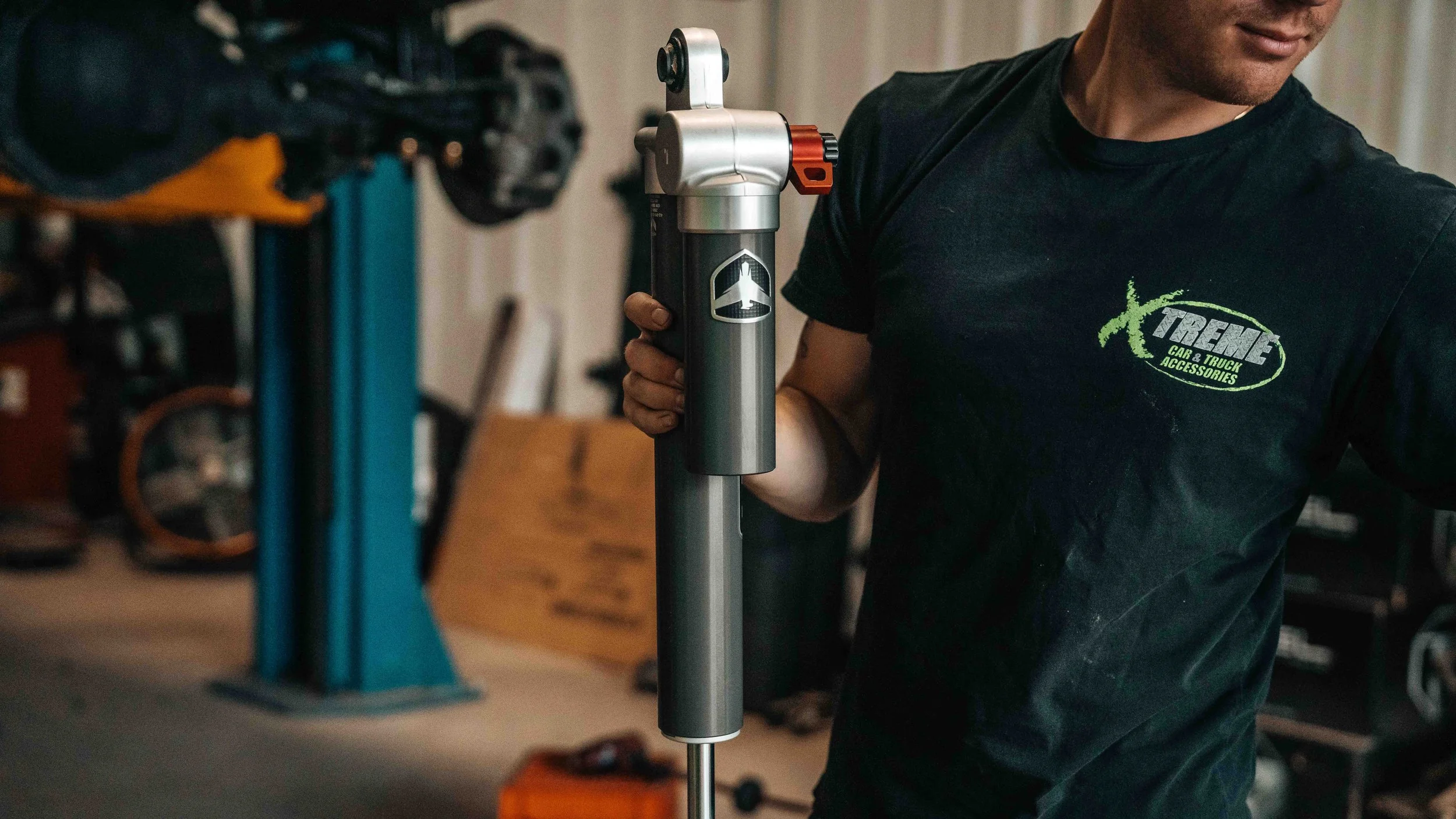 Technician holding a Falcon shock for a GMC Sierra ReadyLIFT 6-inch MAX3 suspension lift installation.