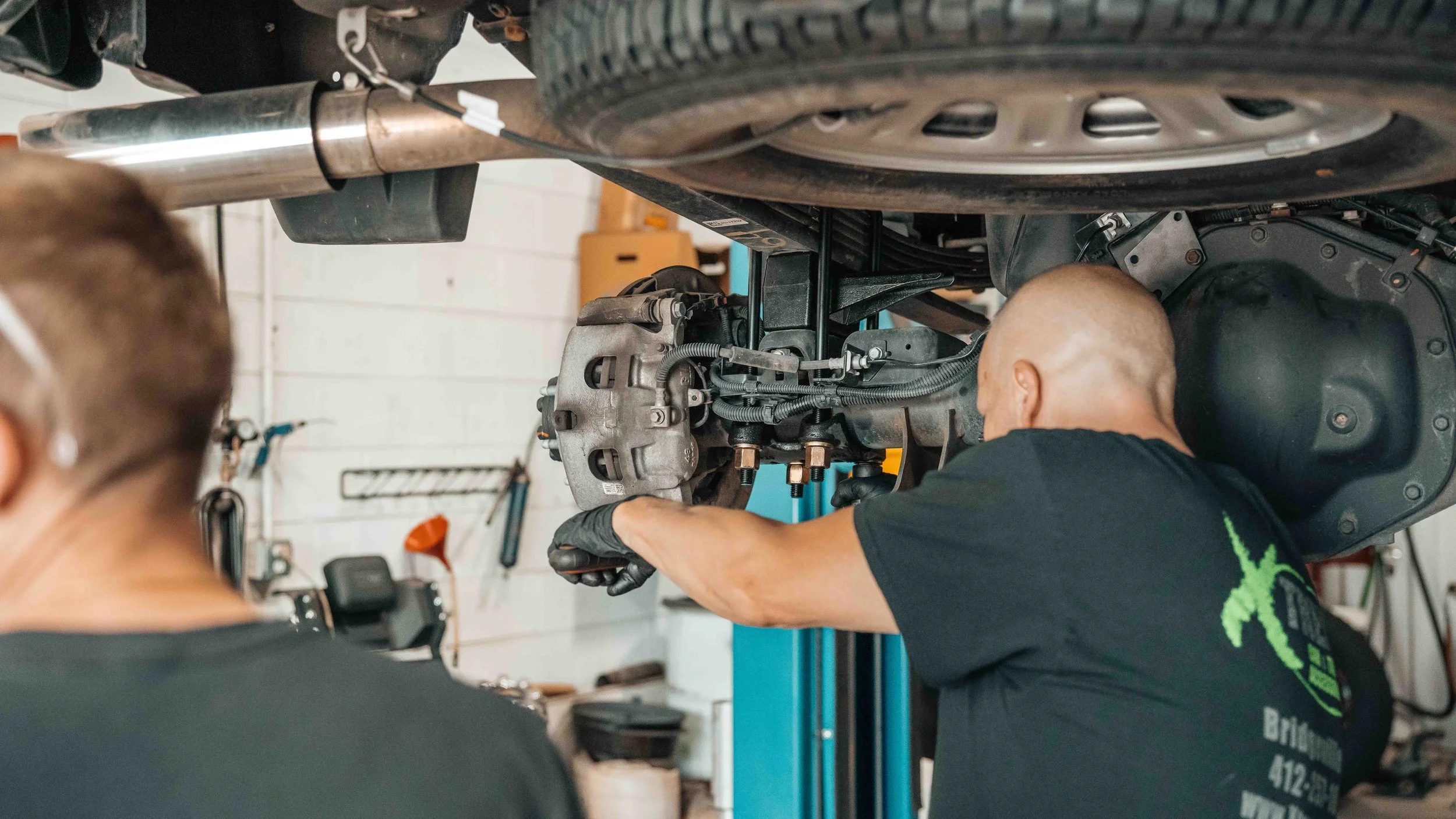 Xtreme Car & Truck technician working on the rear suspension of a GMC Sierra during a ReadyLIFT 6-inch lift installation.