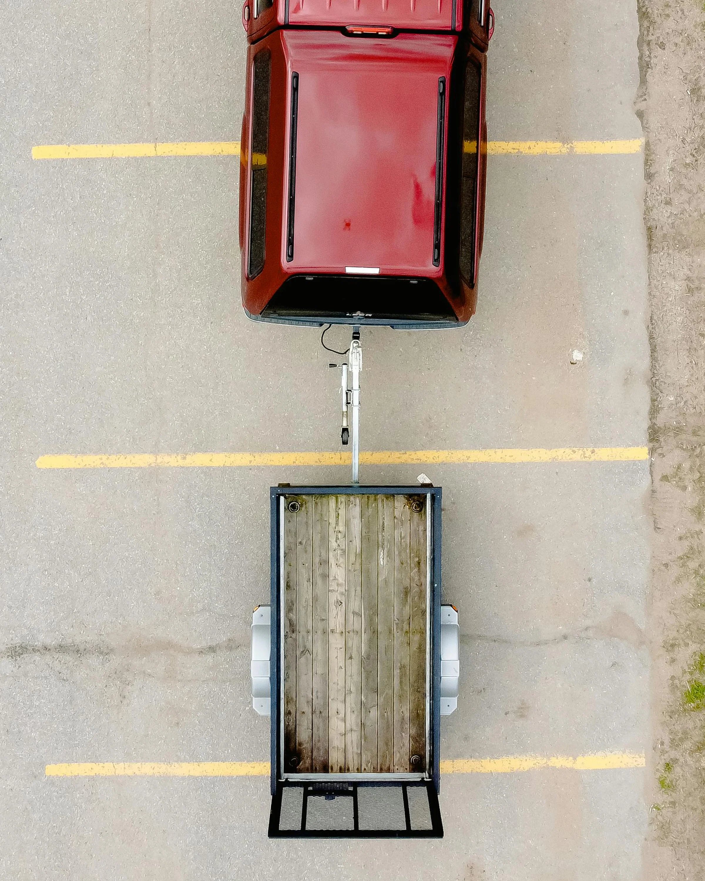 Aerial view of a red vehicle towing a utility trailer, highlighting trailer hitch towing setup installed by Xtreme Car & Truck Accessories in Bridgeville, PA serving Pittsburgh and the South Hills