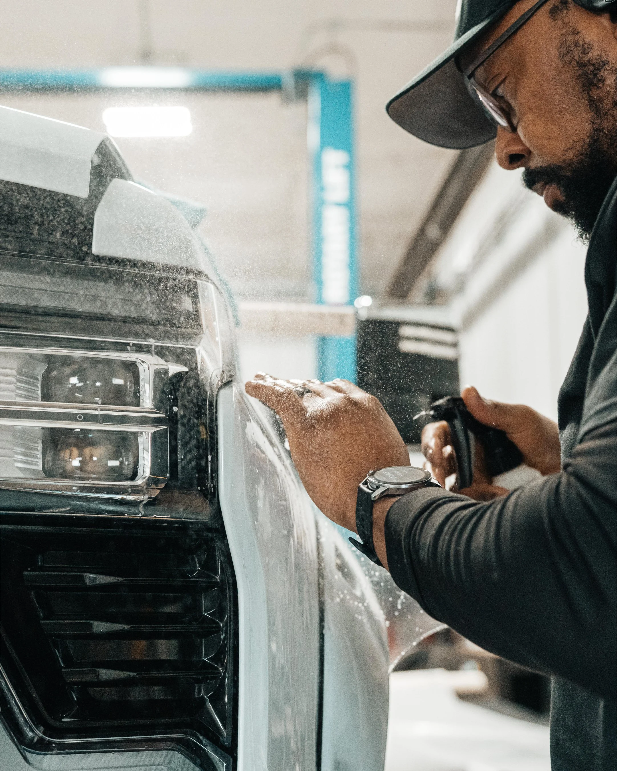 Technician installing XEL paint protection film (PPF) on the front fender of a truck at Xtreme Car & Truck Accessories.