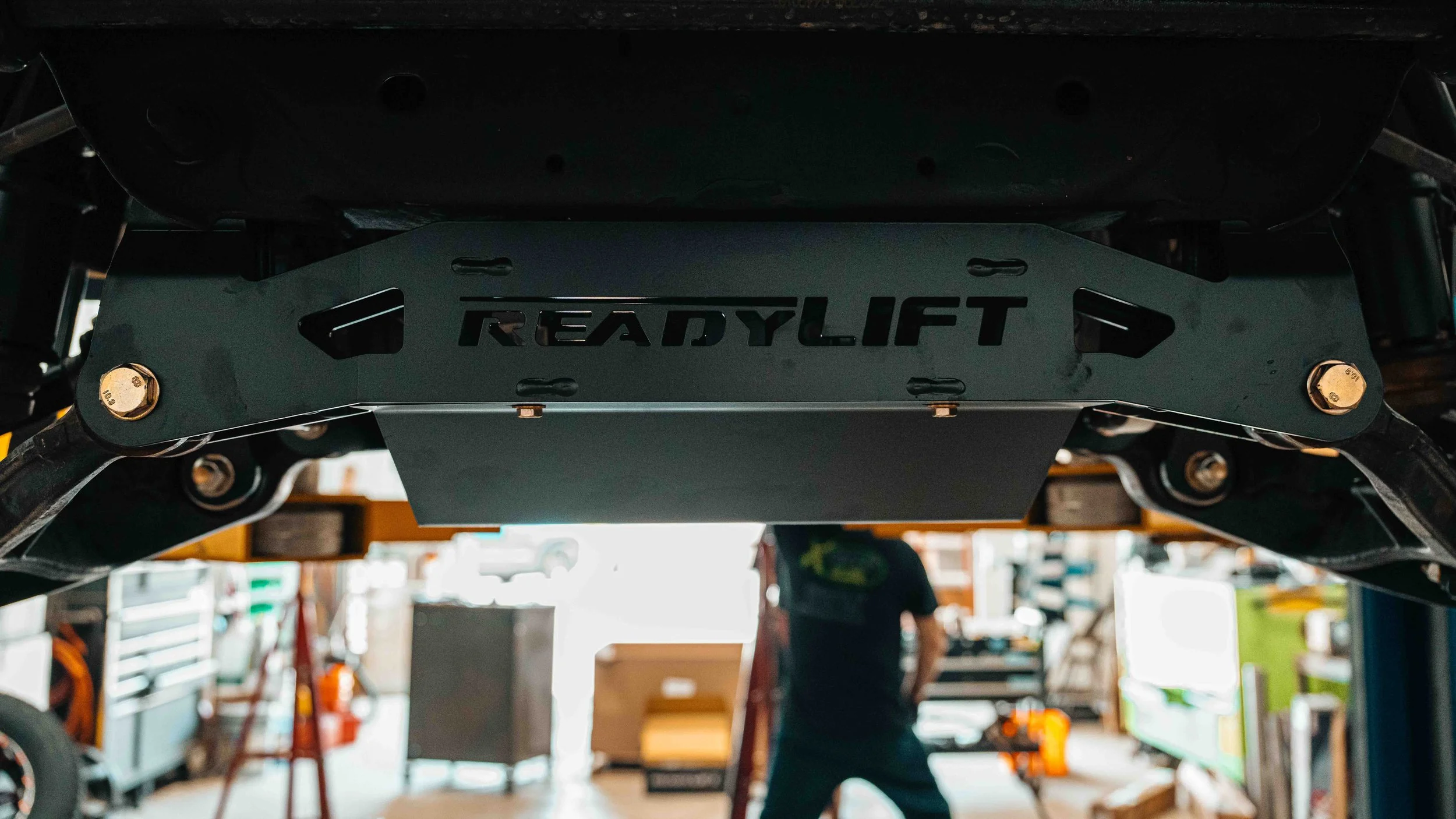 ReadyLIFT crossmember and bracket installed underneath a GMC Sierra during a 6-inch MAX3 suspension lift build.