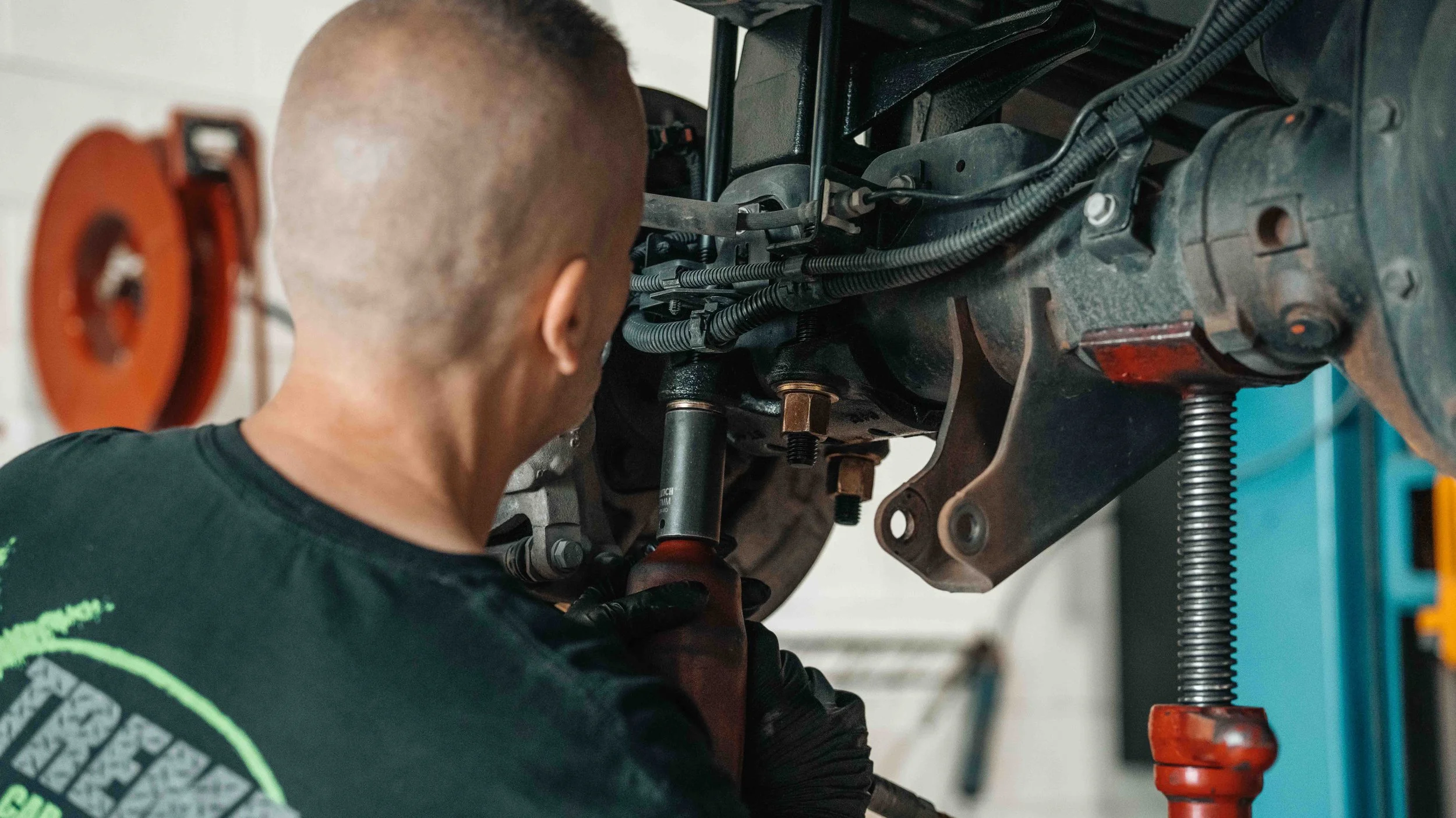Technician working at the rear axle during a ReadyLIFT GMC Sierra 6-inch suspension lift installation in Bridgeville.
