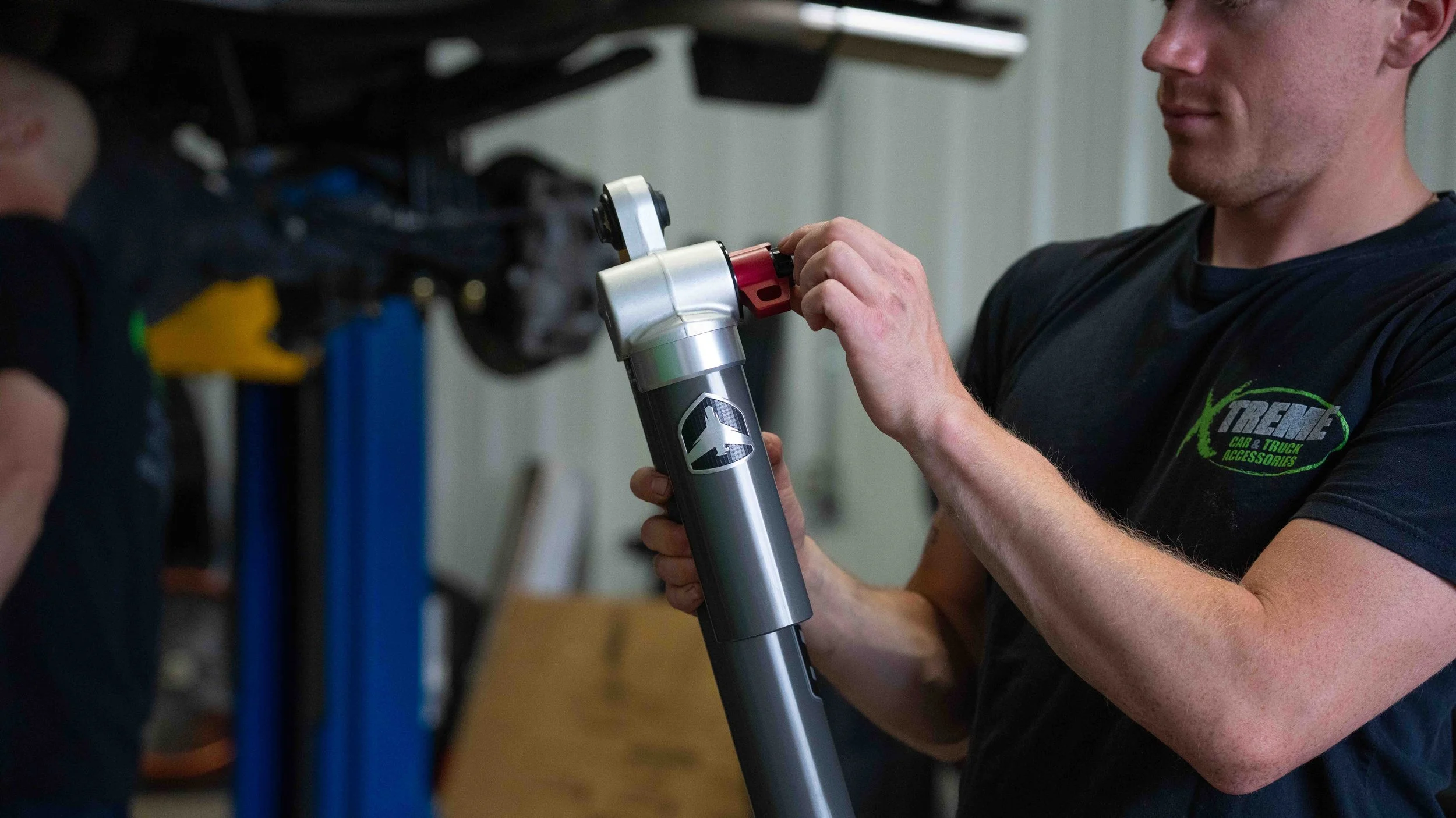 Technician adjusting a Falcon 3.3 shock during a GMC Sierra ReadyLIFT suspension lift installation in Bridgeville, PA.