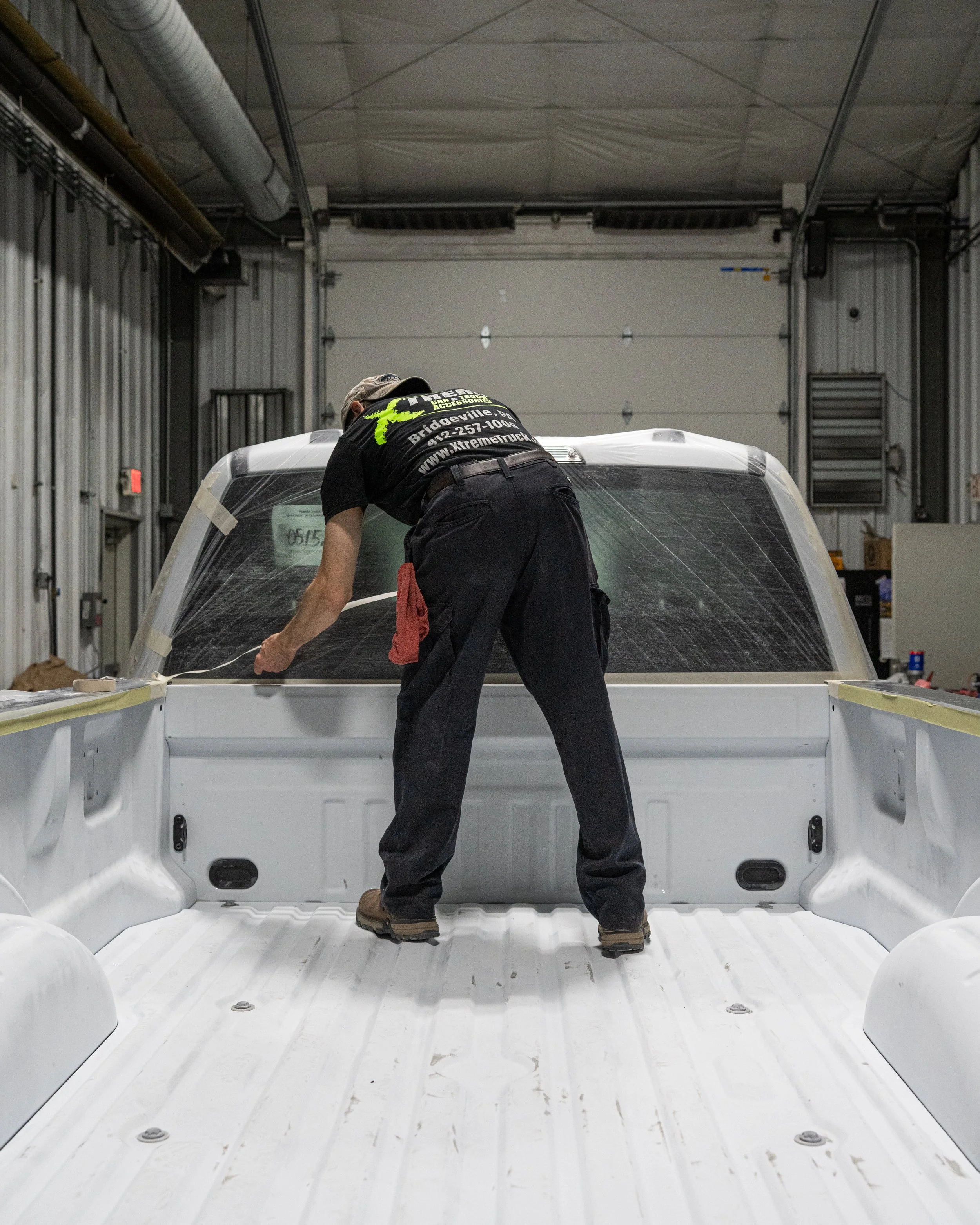 Xtreme Car & Truck Accessories technician prepping a white pickup truck bed for professional spray-in bedliner installation in Bridgeville, PA.