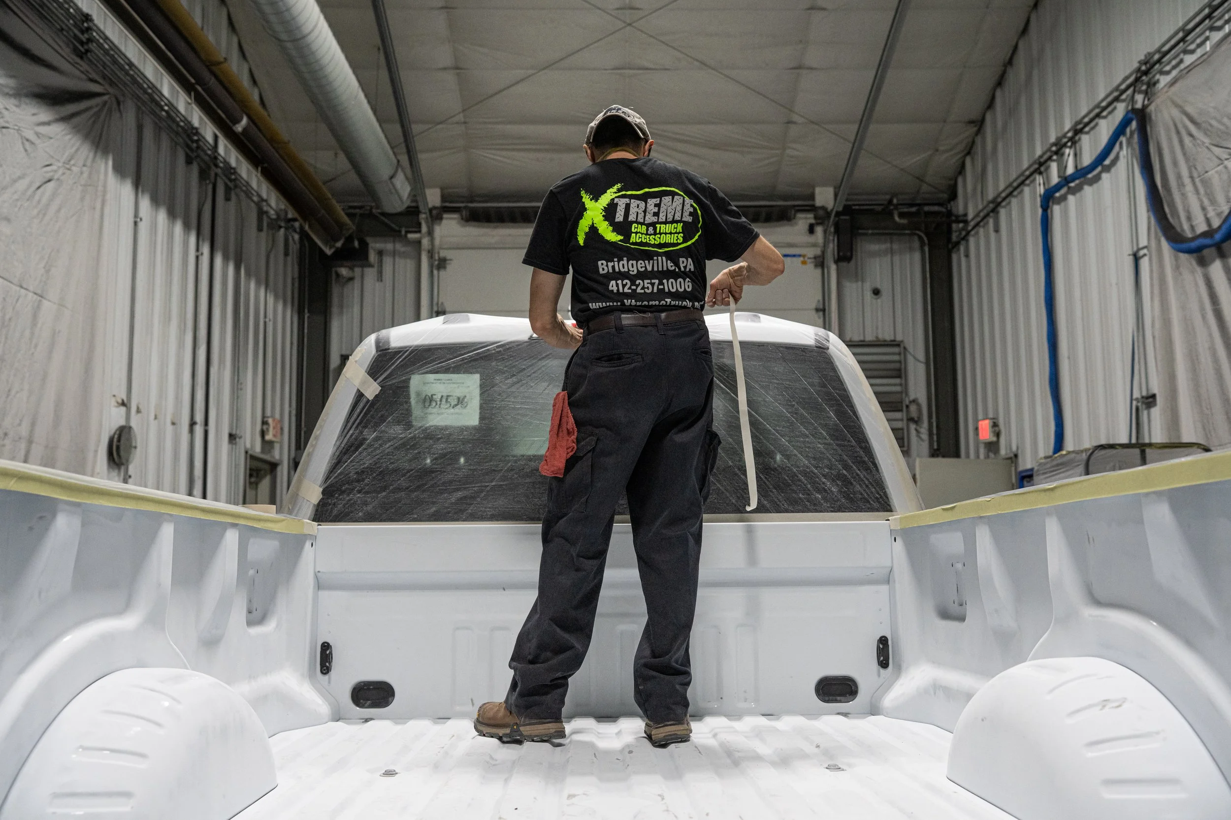 Xtreme Car & Truck Accessories technician masking and prepping a pickup truck bed for spray-in bed liner installation in Bridgeville, PA.
