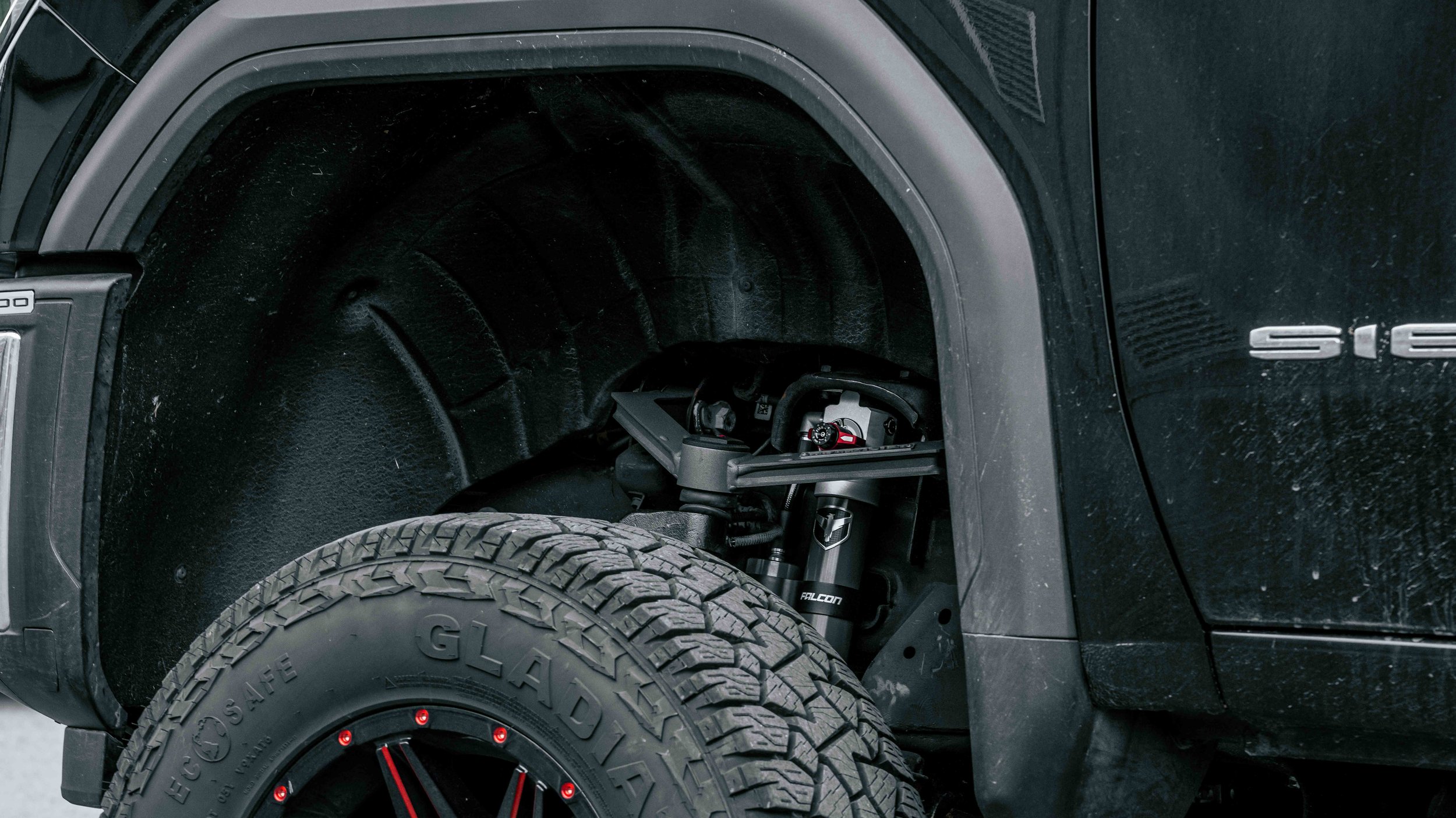 Front wheel well of a lifted GMC Sierra showing Falcon shock hardware after ReadyLIFT 6-inch MAX3 installation.
