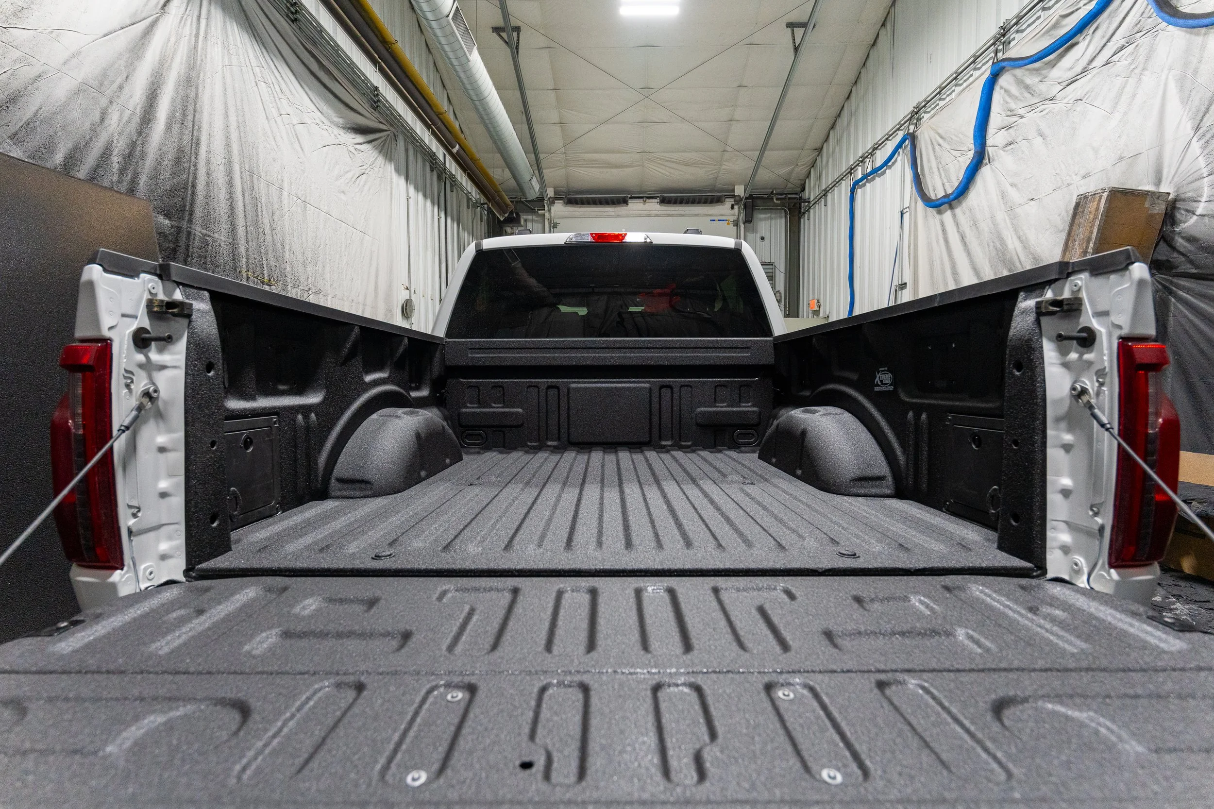 Freshly installed spray-in bed liner with textured protective coating inside a pickup truck bed, tailgate down