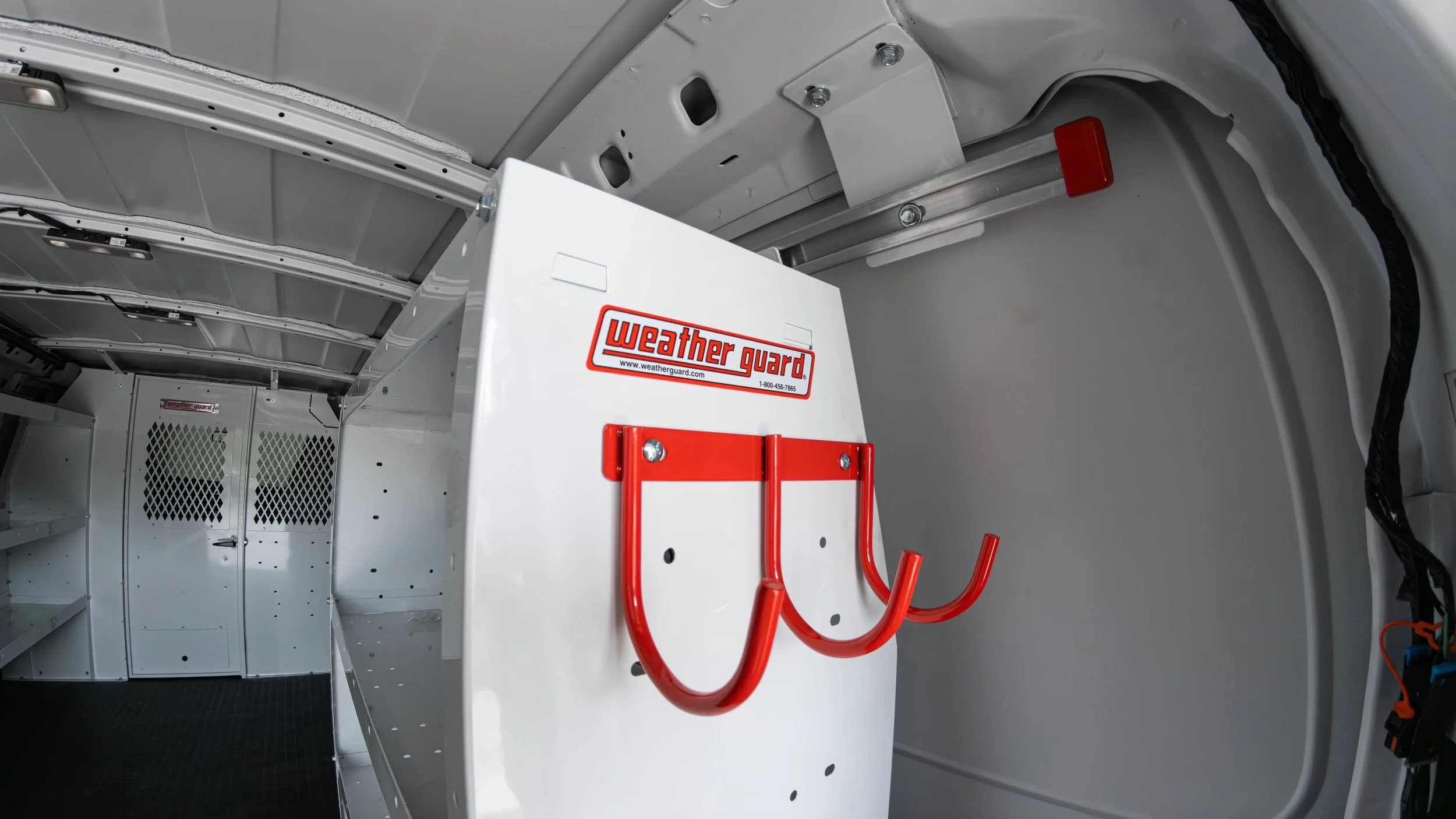 Close-up of WeatherGuard red tool hooks mounted to the end panel of a van shelving unit in a Chevy Express