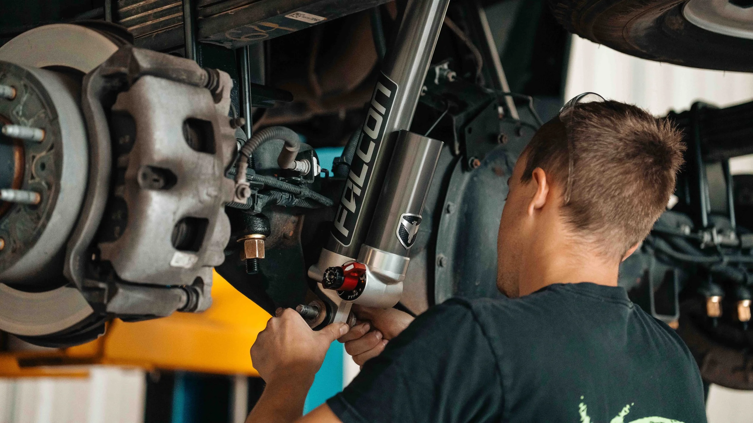 Technician installing a Falcon shock on a GMC Sierra ReadyLIFT 6-inch MAX3 suspension lift at Xtreme Car & Truck.