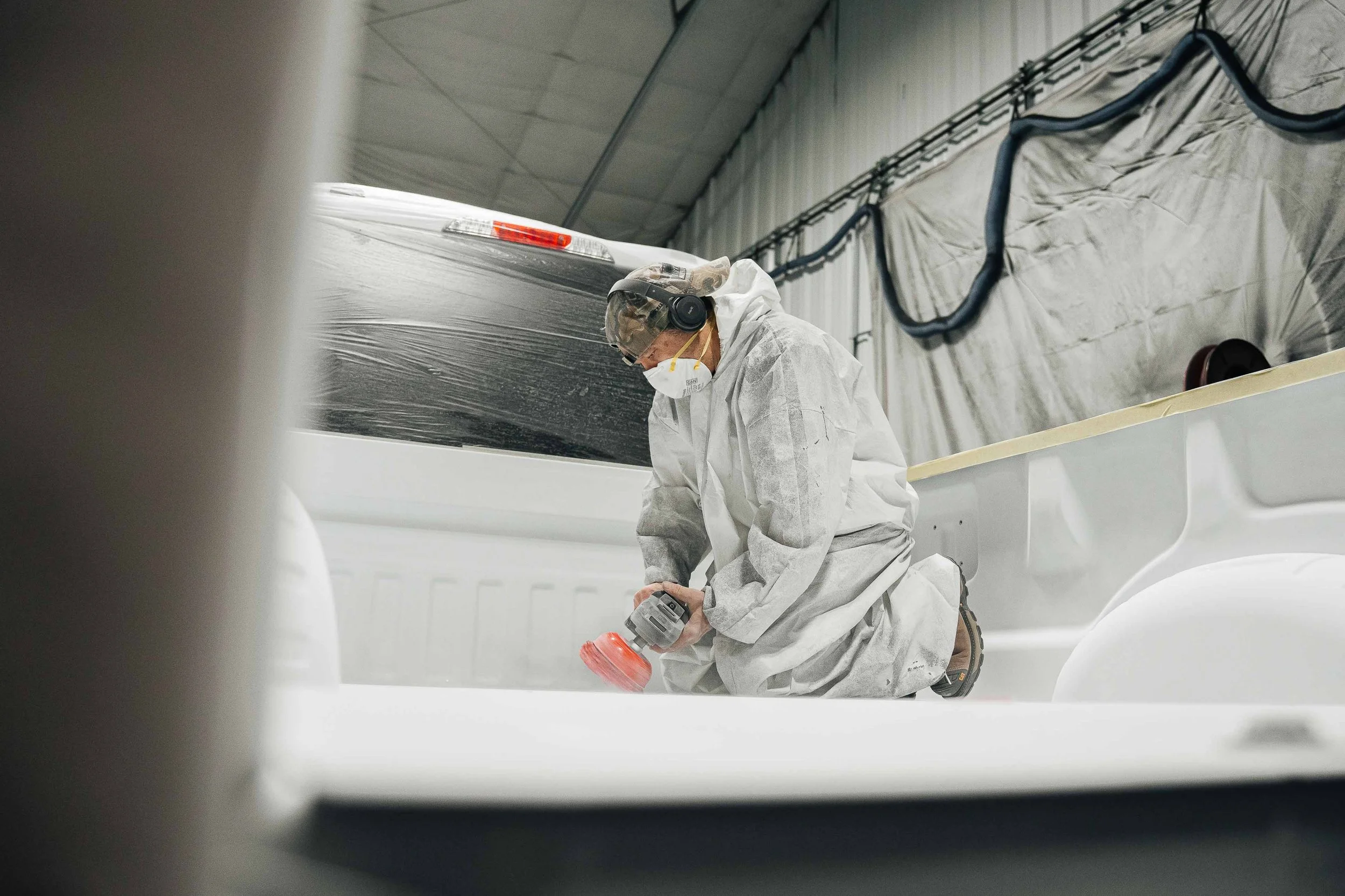Xtreme Car & Truck Accessories technician sanding and prepping a pickup truck bed before spray-in bed liner installation in Bridgeville, PA.